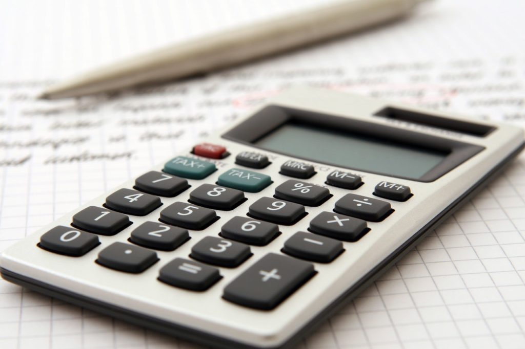 calculator and pen on sheet of paper depicting financial information. 