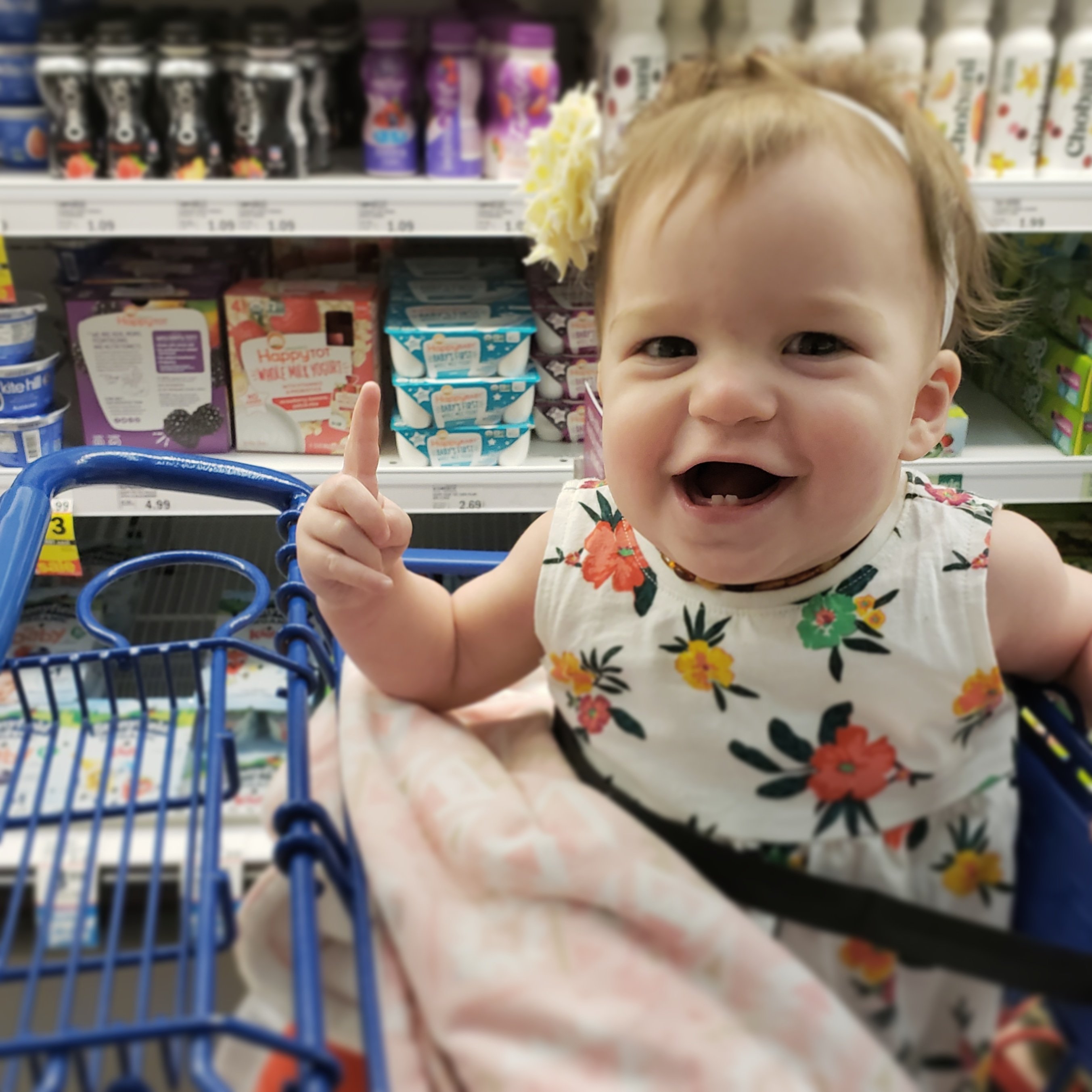 happy smiling baby girl sitting in a shopping cart in a grocery store