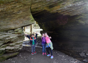 three children stand under the natural land bridge