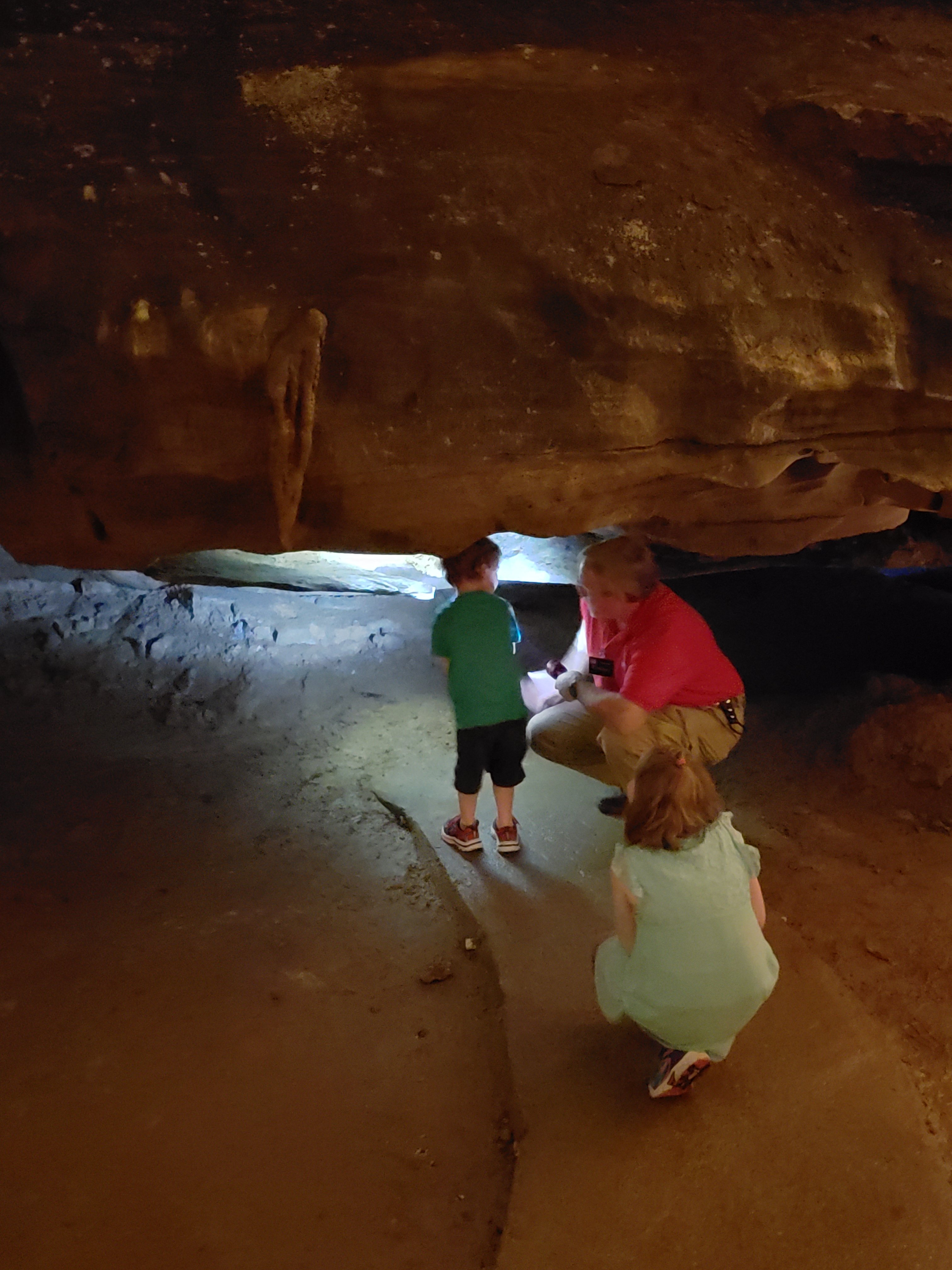 a tour guide showing kids are tight space in the caves