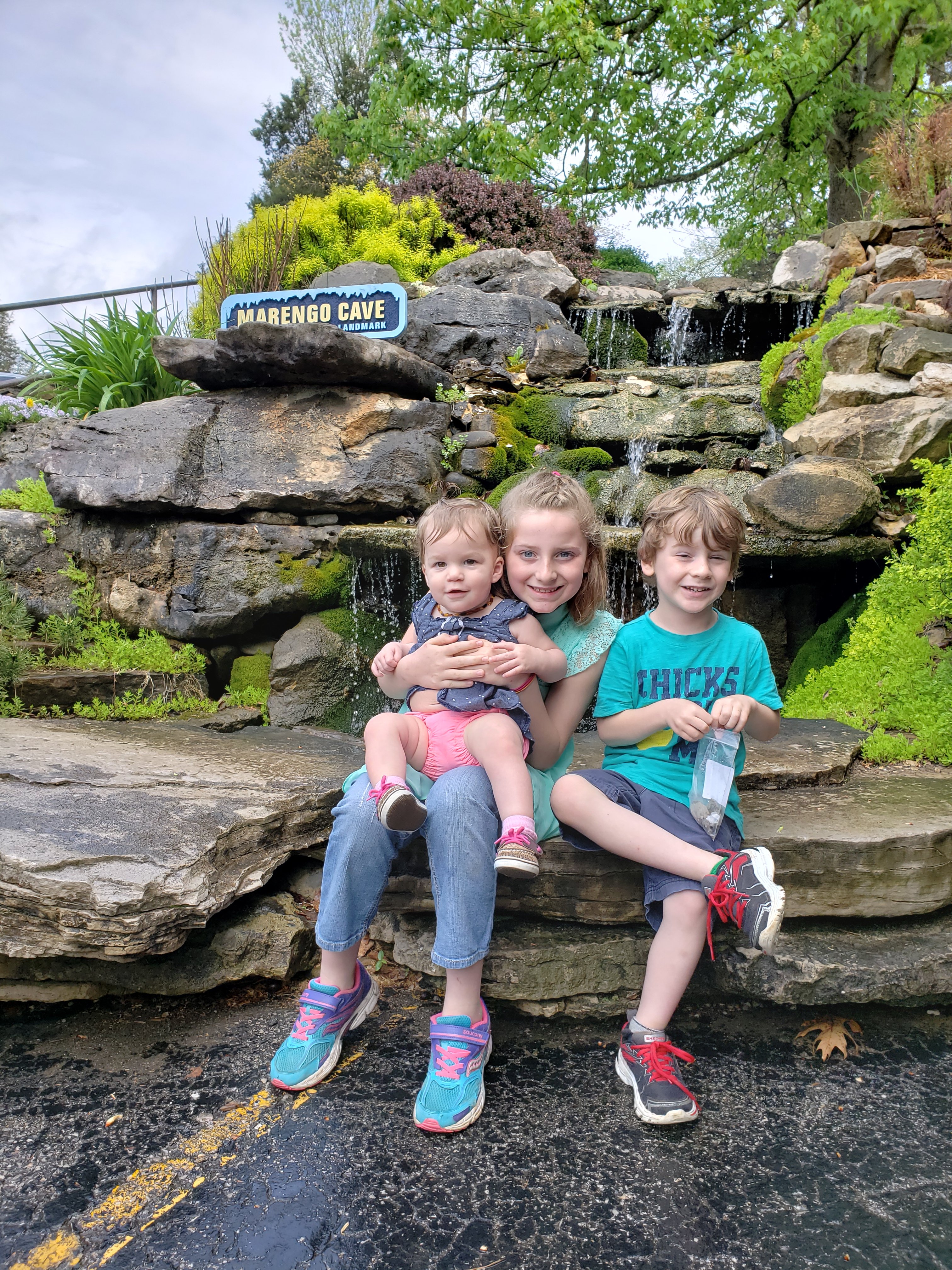 three kids sitting in front of a waterfall at Marengo Cave