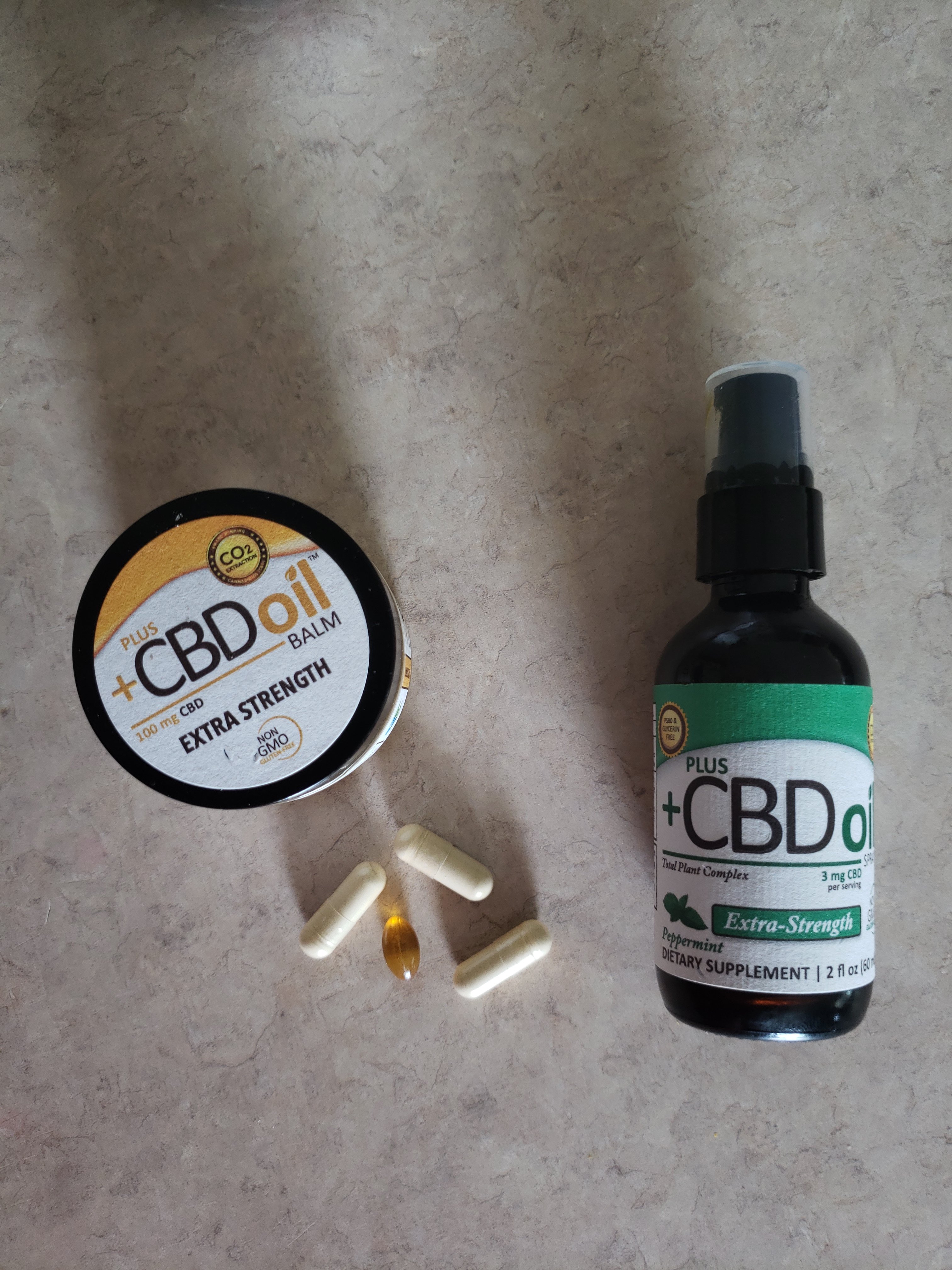 +CBD oil balm, spray, and pills laying on a counter top