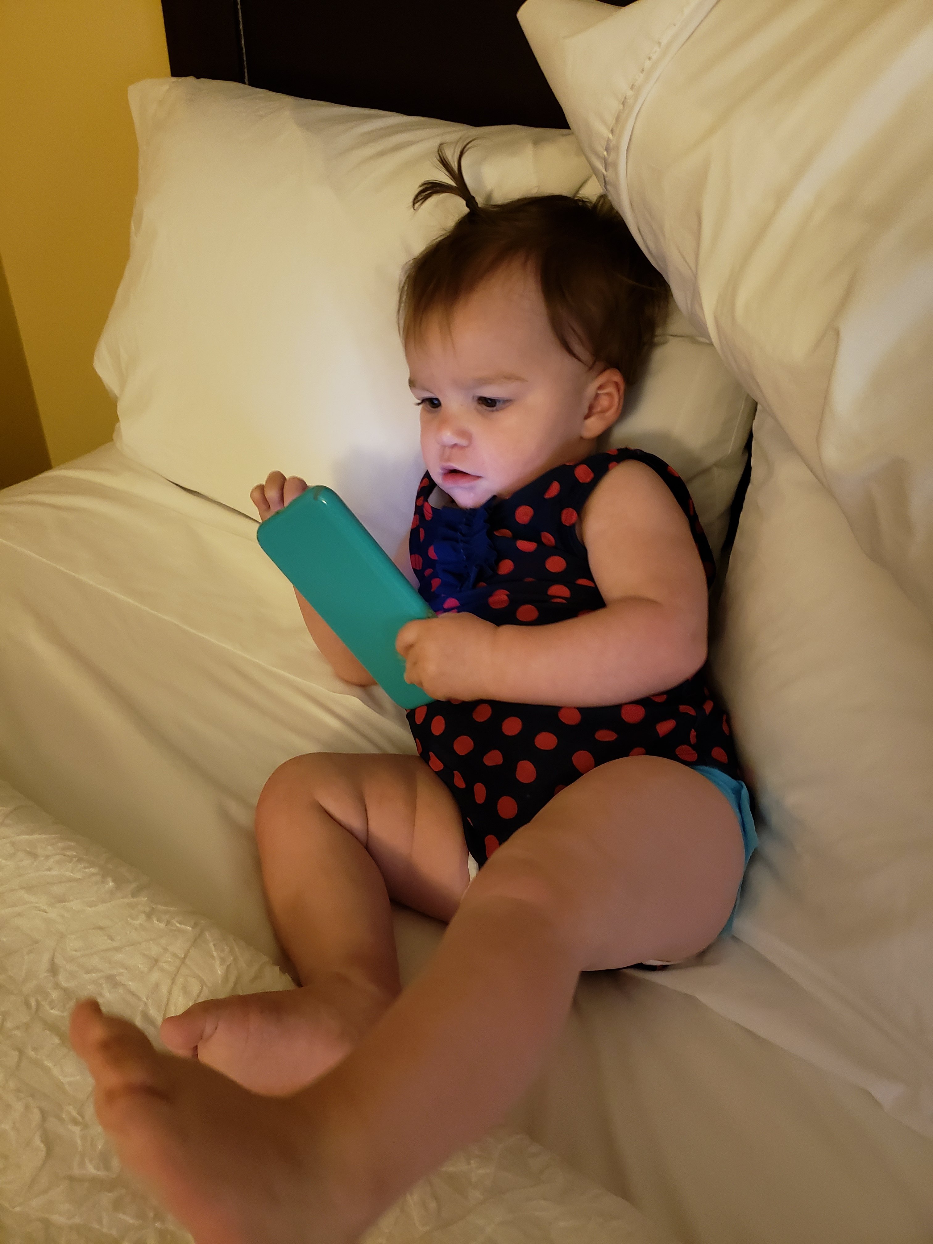 toddler girls laying back on pillows looking at a cellphone