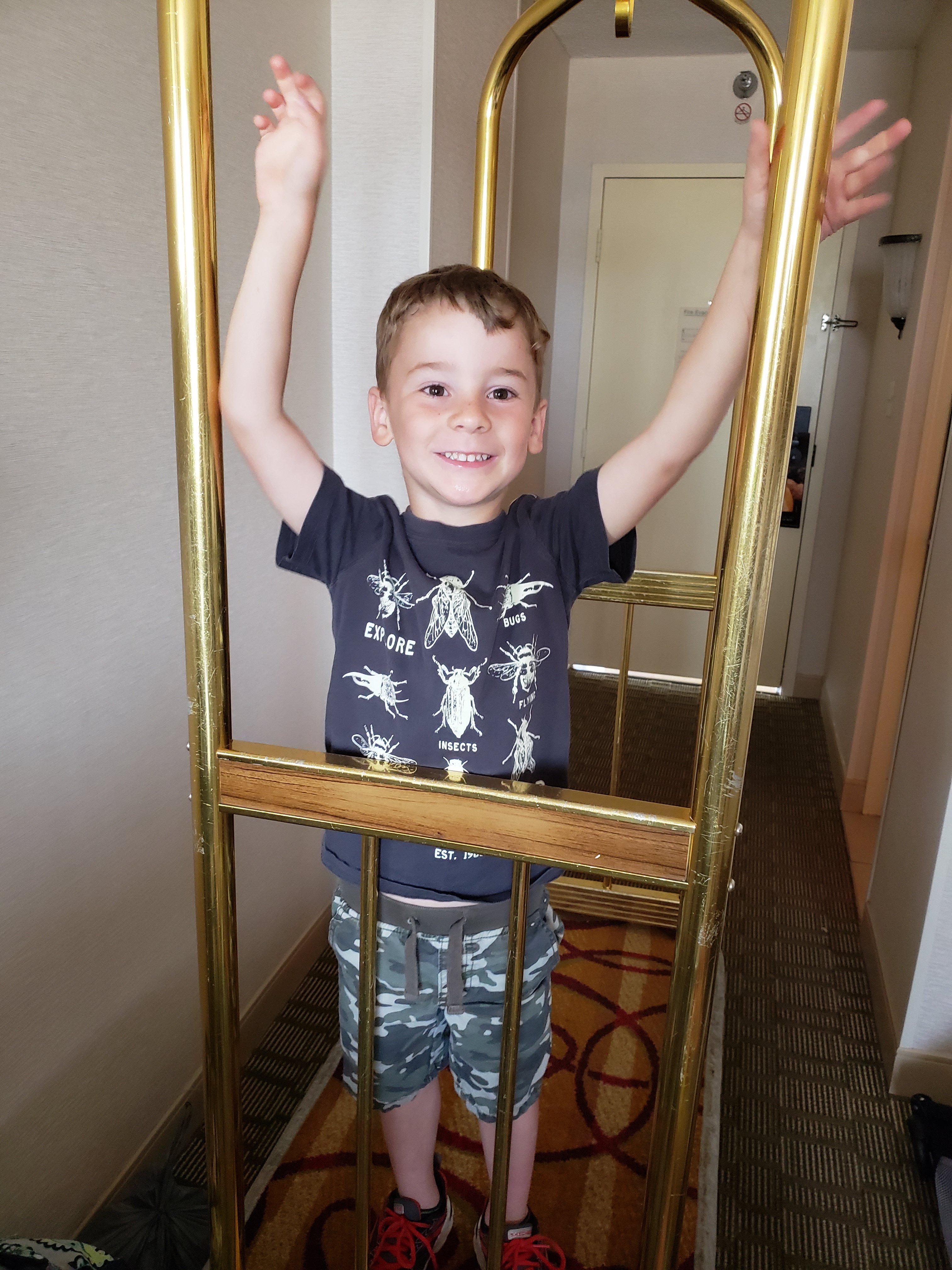 boy standing on a hotel luggage cart