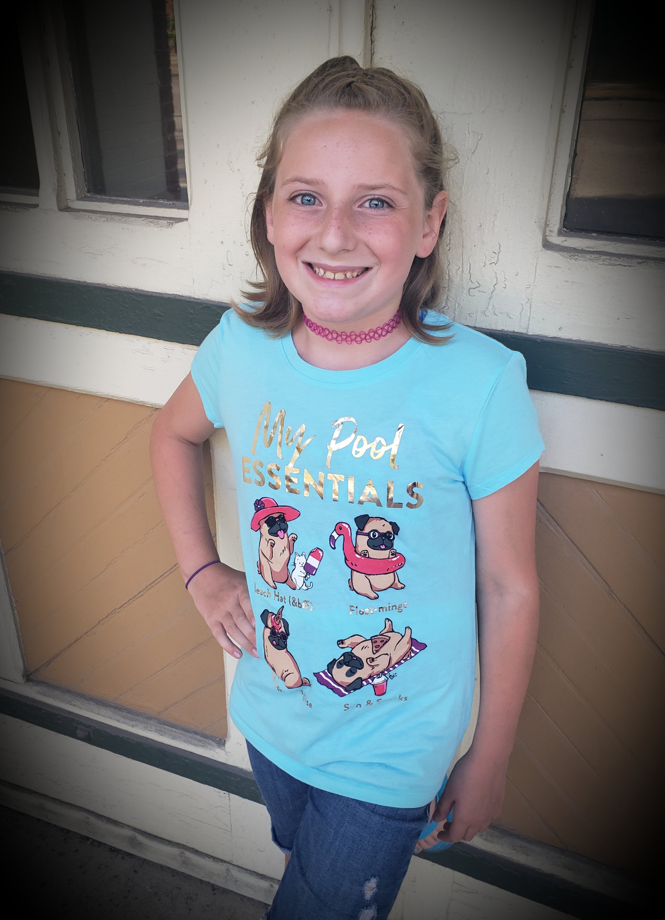 preteen girl smiling at the camera standing in front of a building