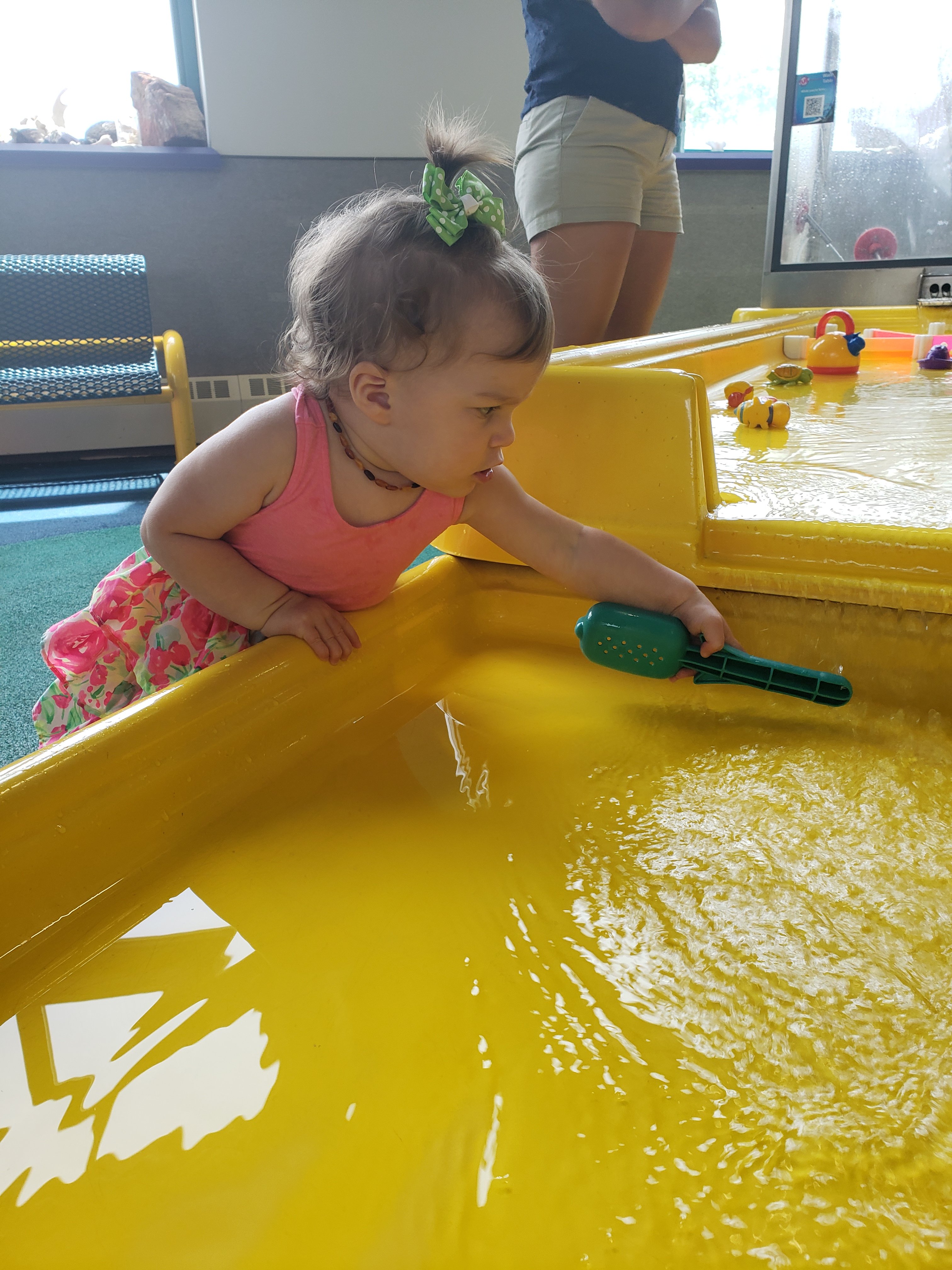 a young girl playing in at a water table