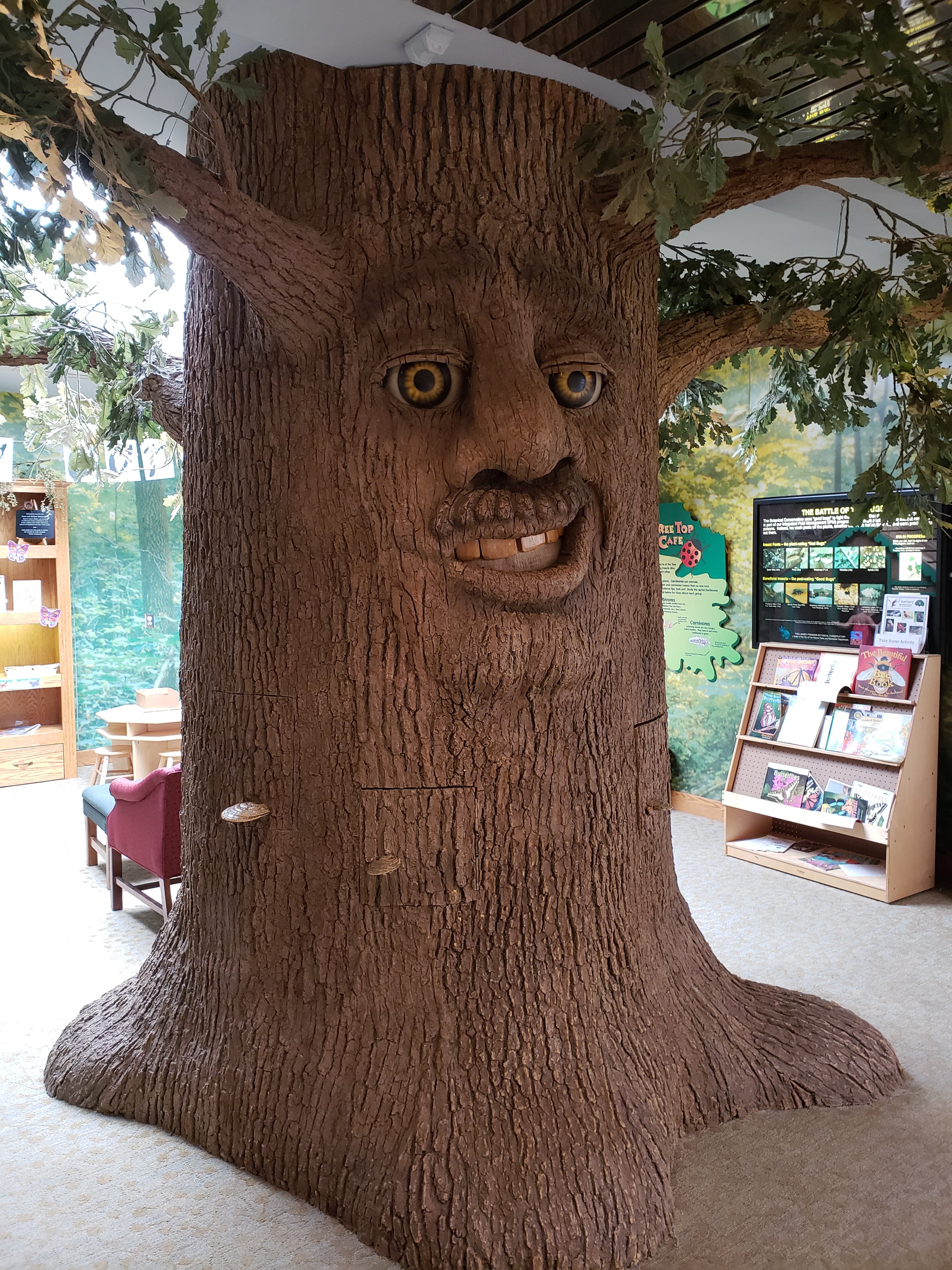 a large fake tree with a face in an indoor space