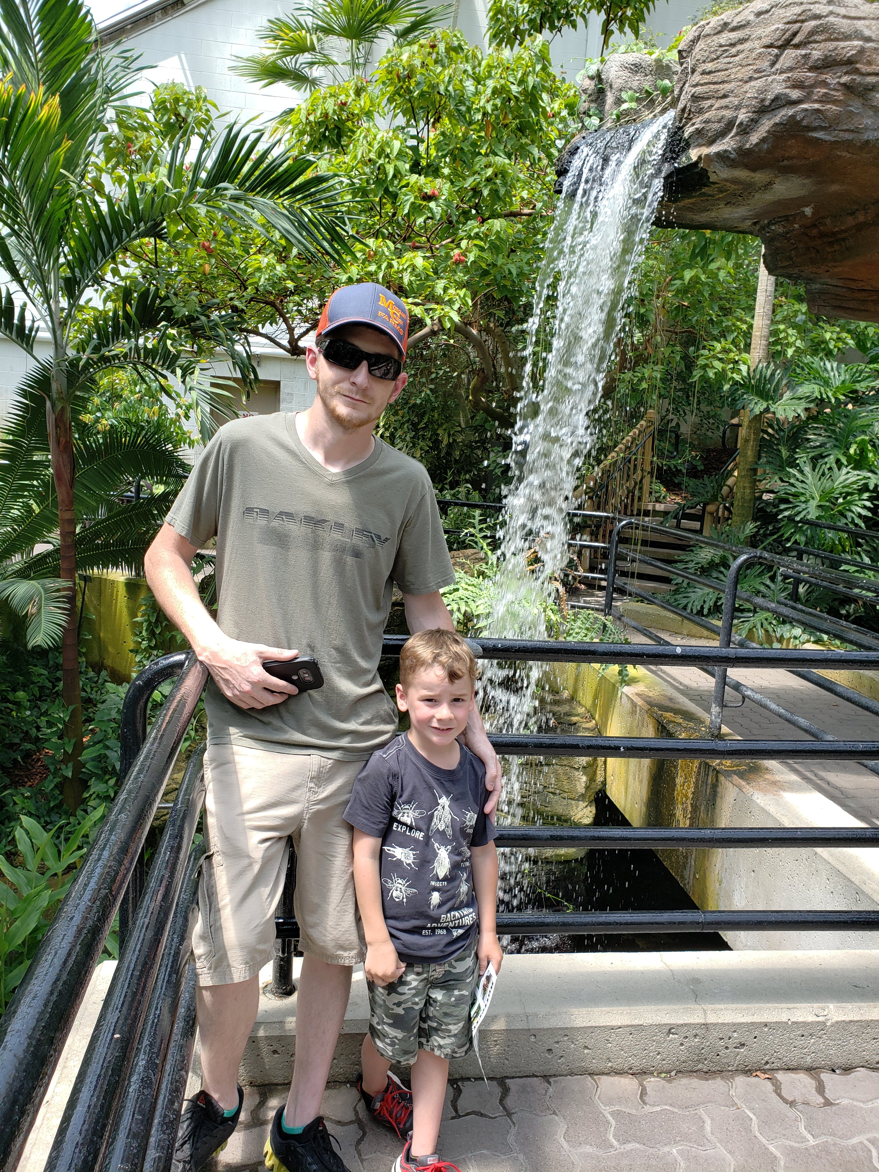 man and child standing on a look off with a small waterfall behind them