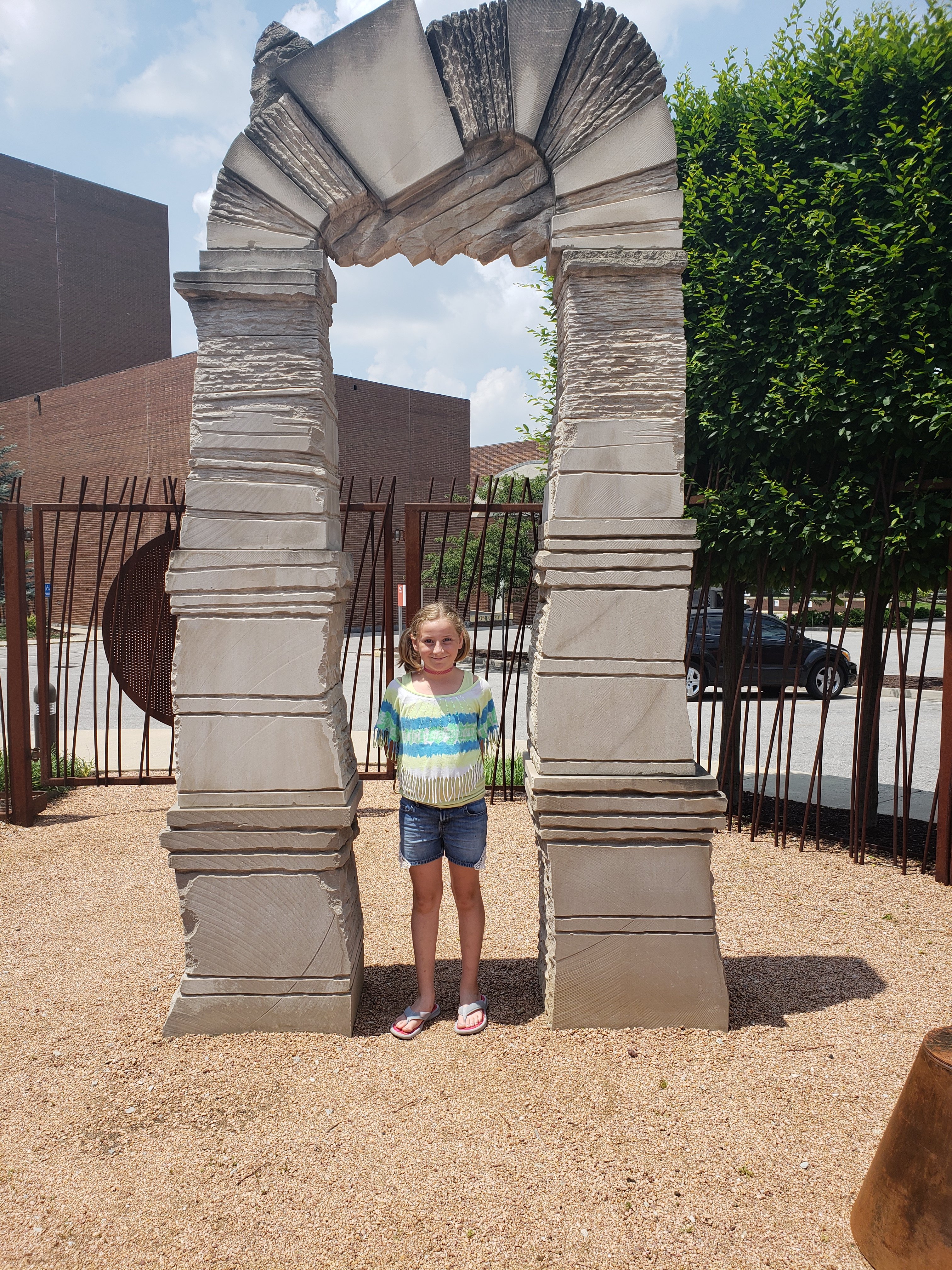 a girl standing in a large arching sculpture