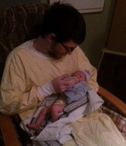 man giving a newborn baby a bottle in the hospital