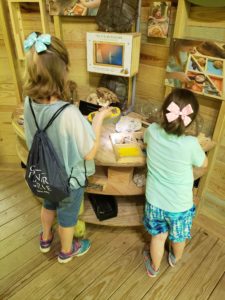 two girls standing at a table exploring different materials