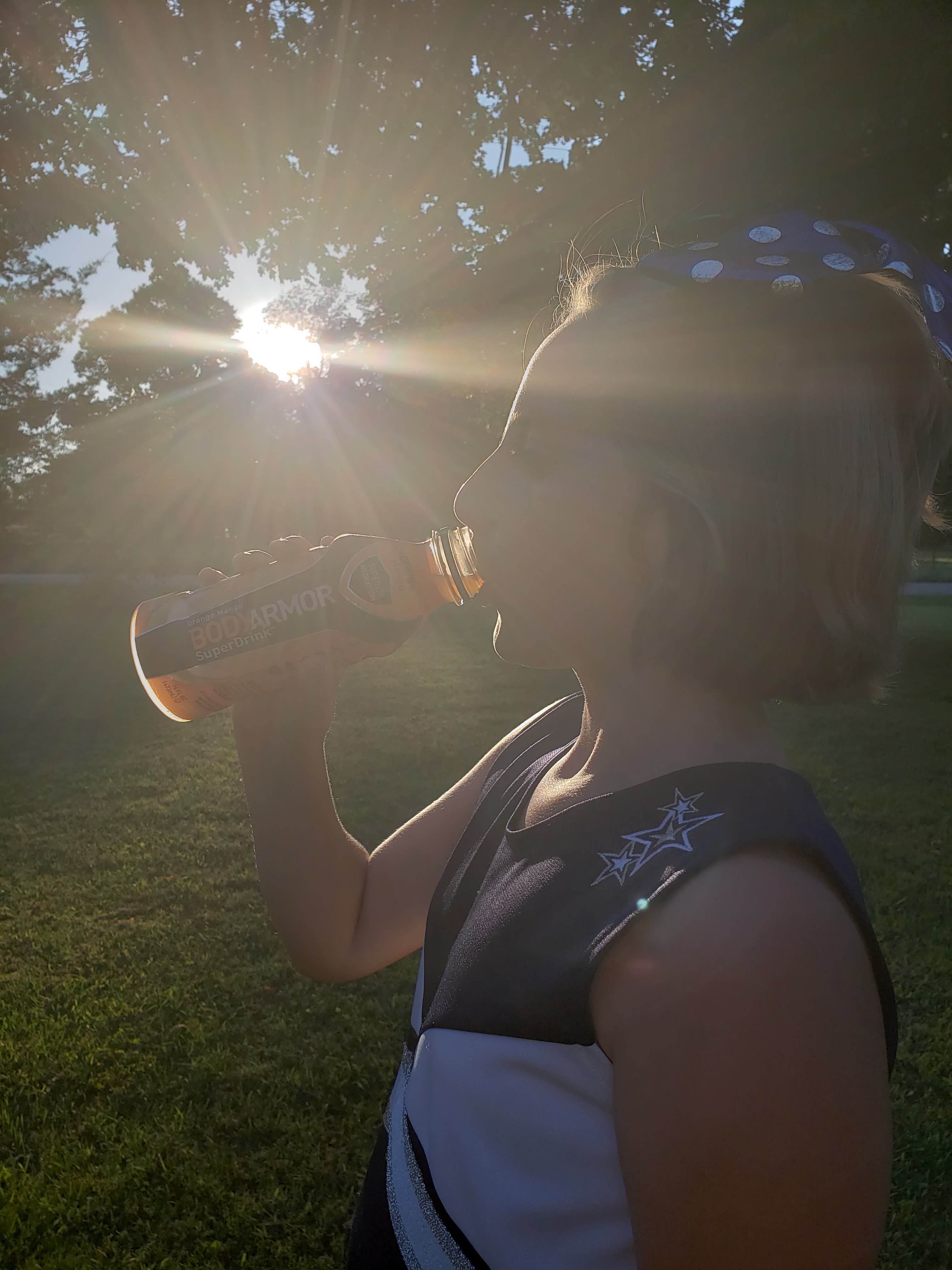 teen cheerleader drinking BodyAmor SuperDrink outside in the sunshine