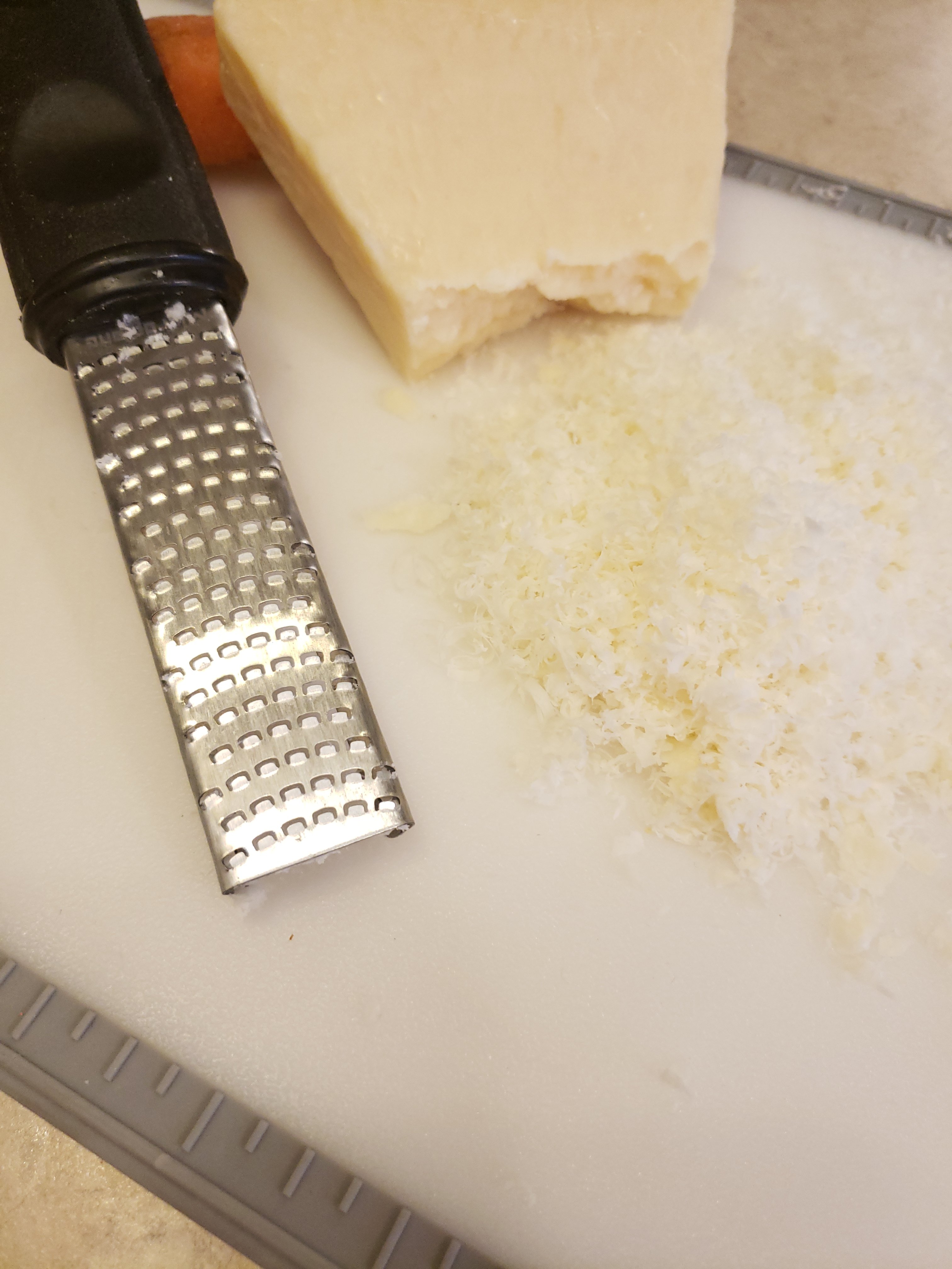 stella cheese, grater, on a white cutting board