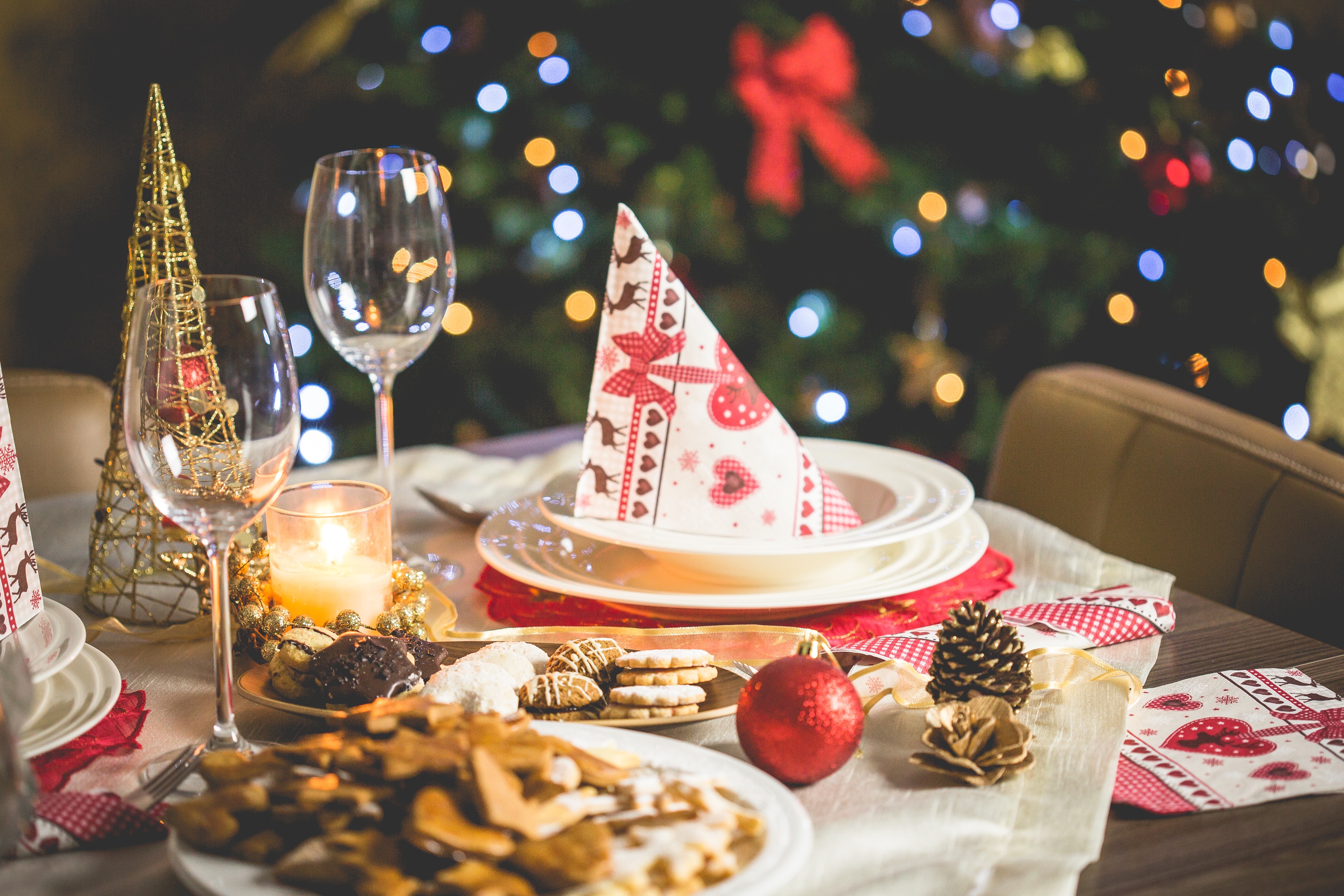 table set for a Christmas meal with a Christmas tree in the background