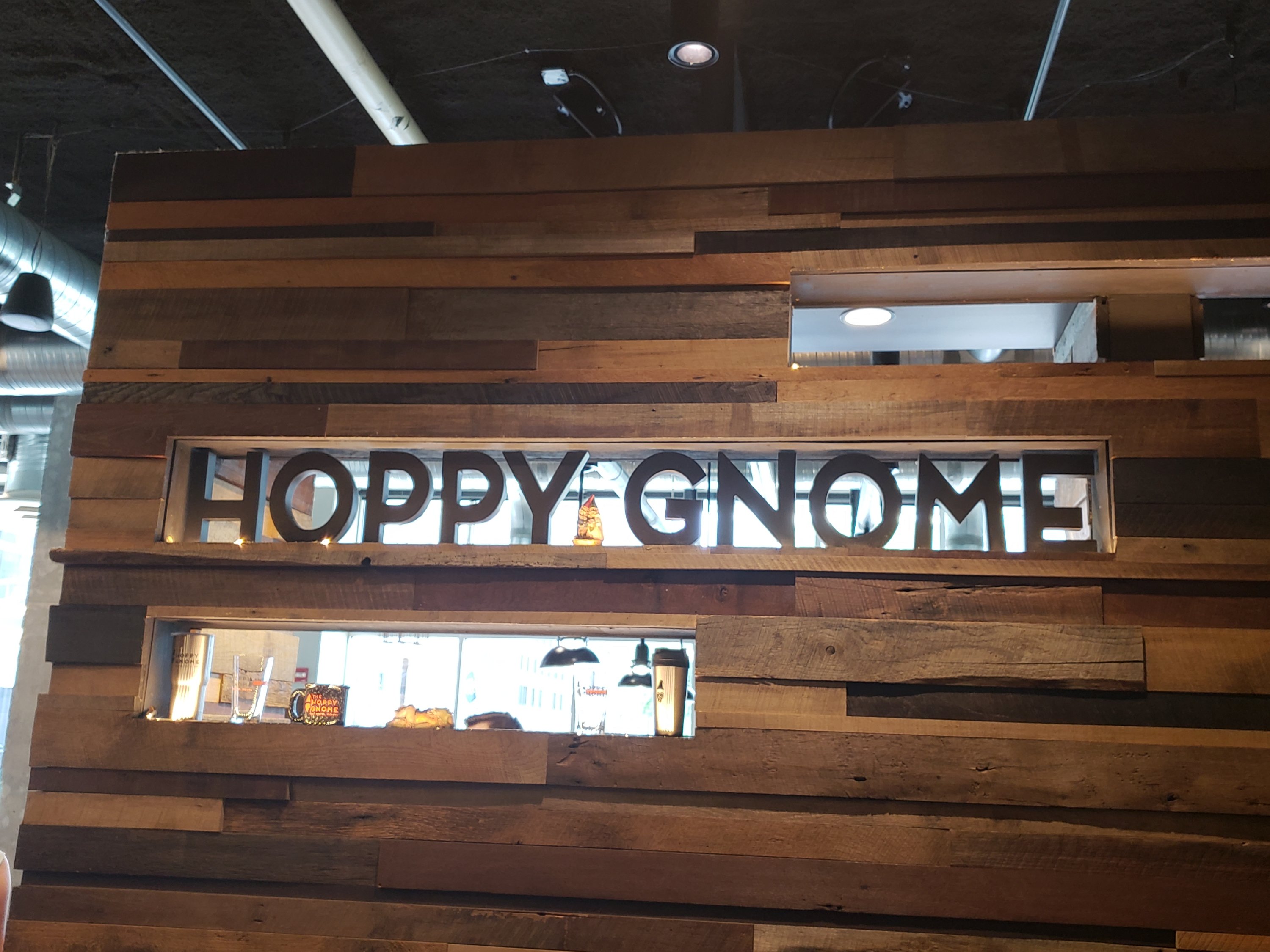 A decorative wood covered wall with some cut outs. Hoppy Gnome wooden letters in one of the cut outs