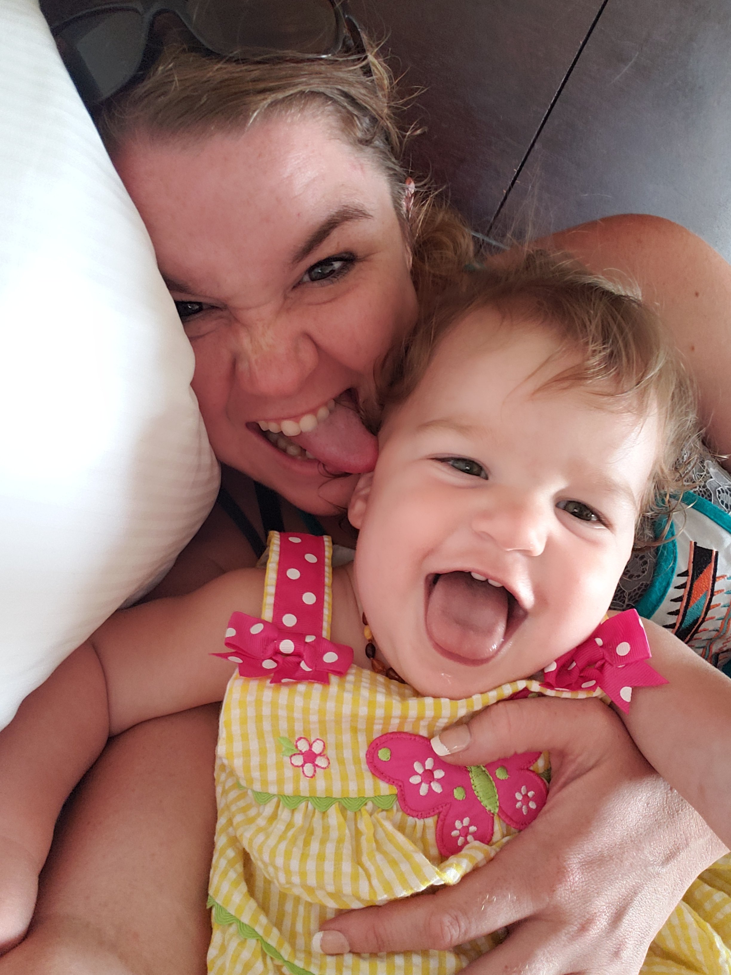 mom and baby girl making silly faces at the camera in a hotel room