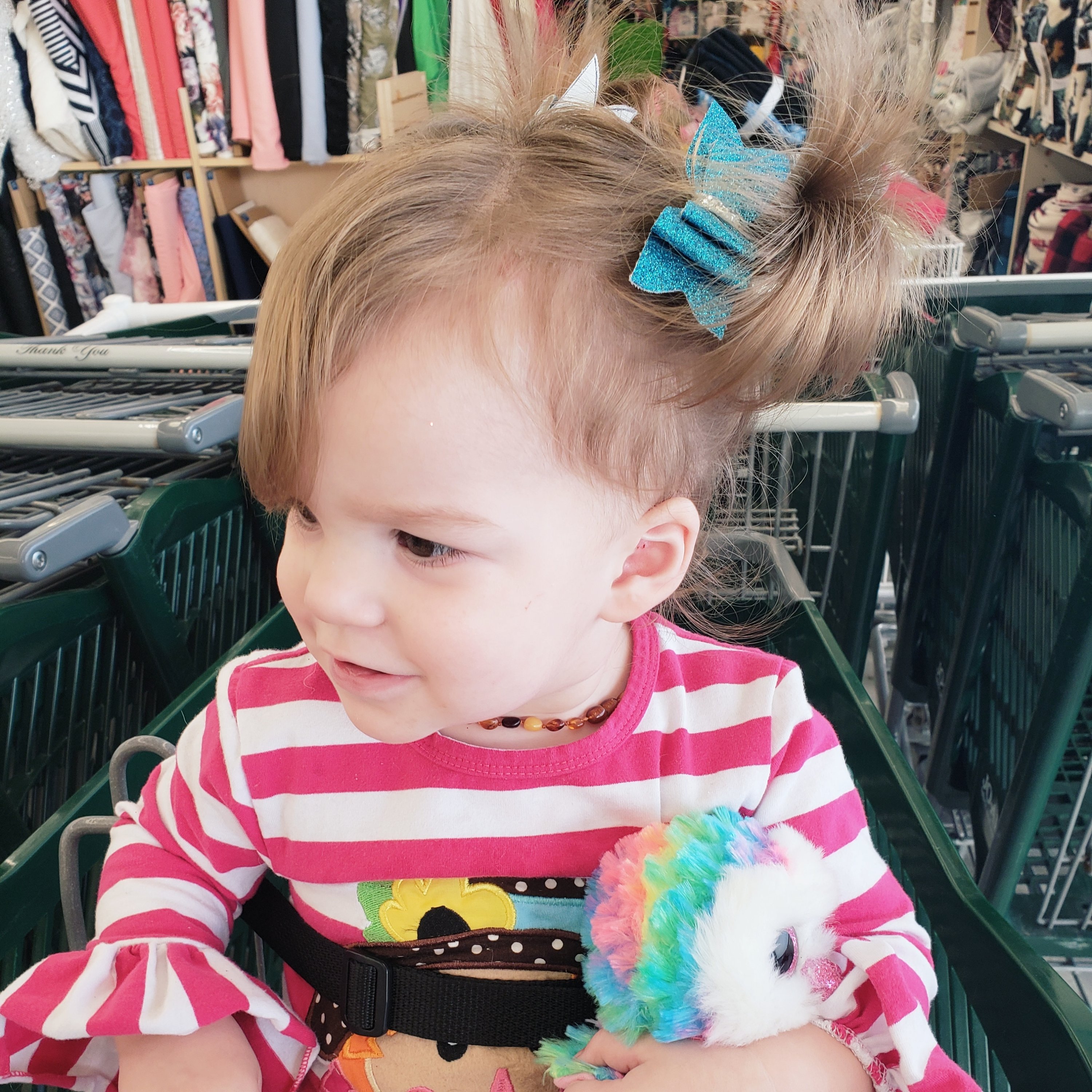 toddler girl sitting in a shopping cart holding a toy