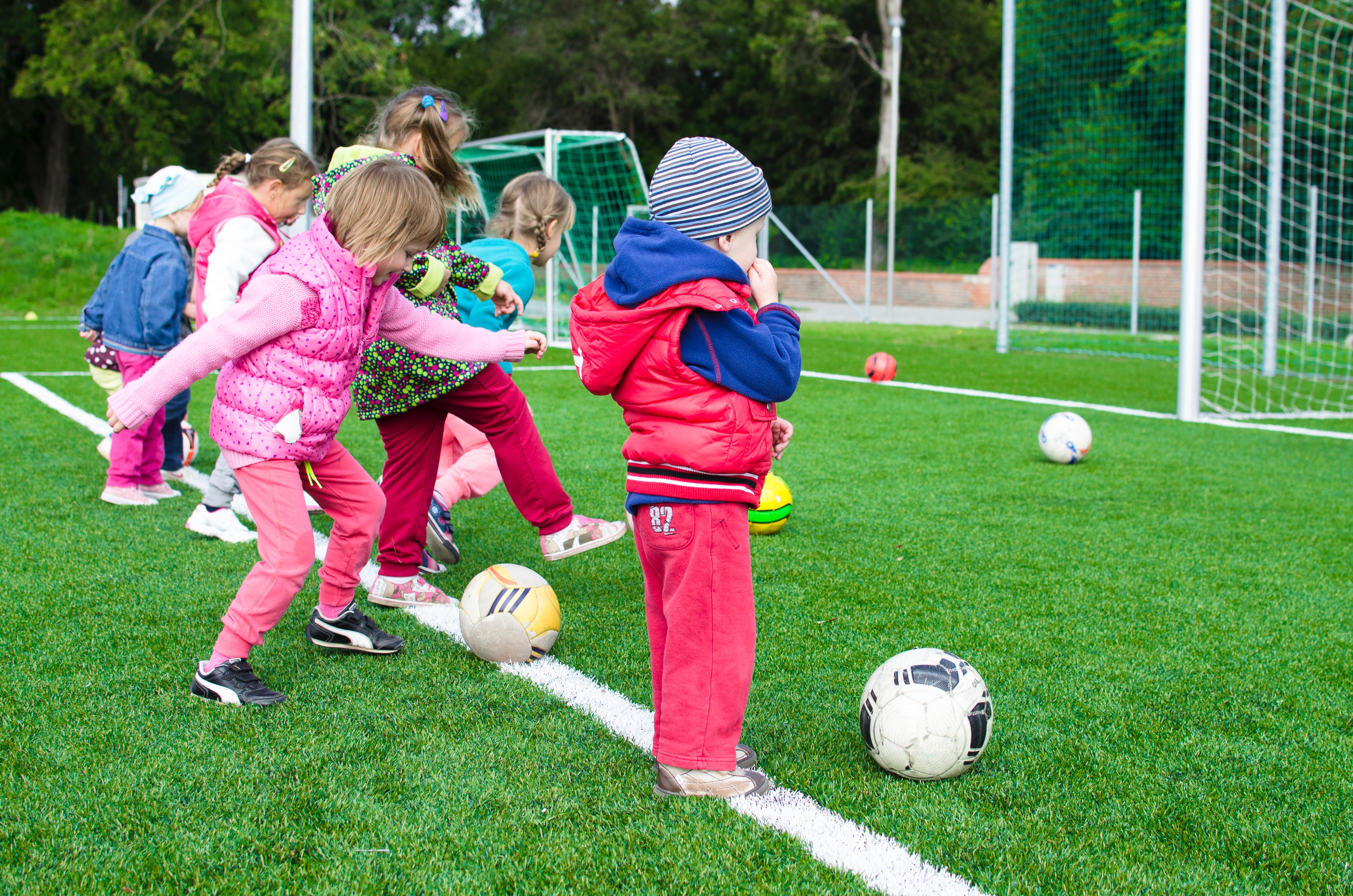 young children kicking soccer balls in a soccer field