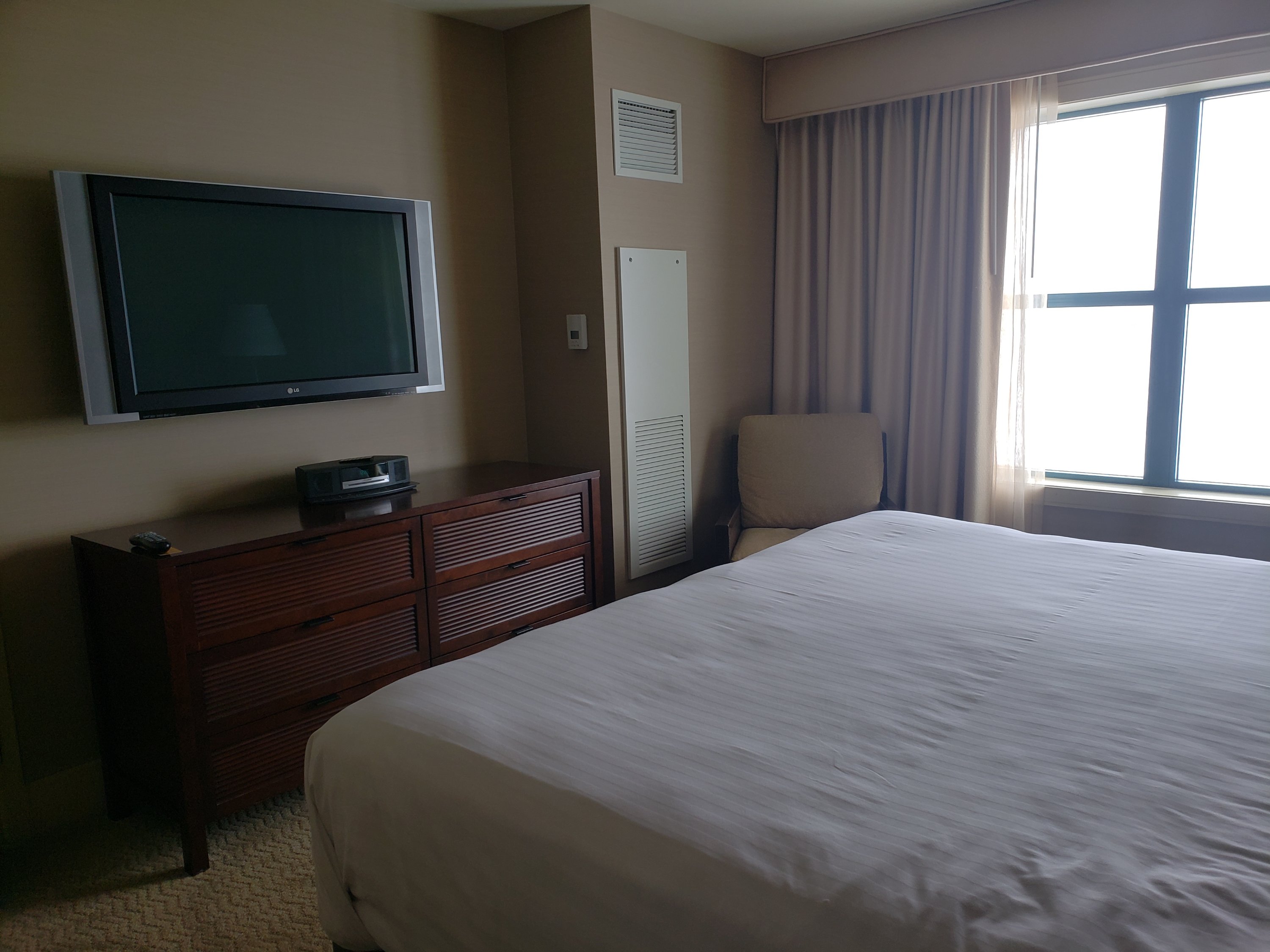 end of the king sized bed, facing at flat screen television mounted on the wall over a dresser at the Isle Casino and Hotel Bettendorf in a room