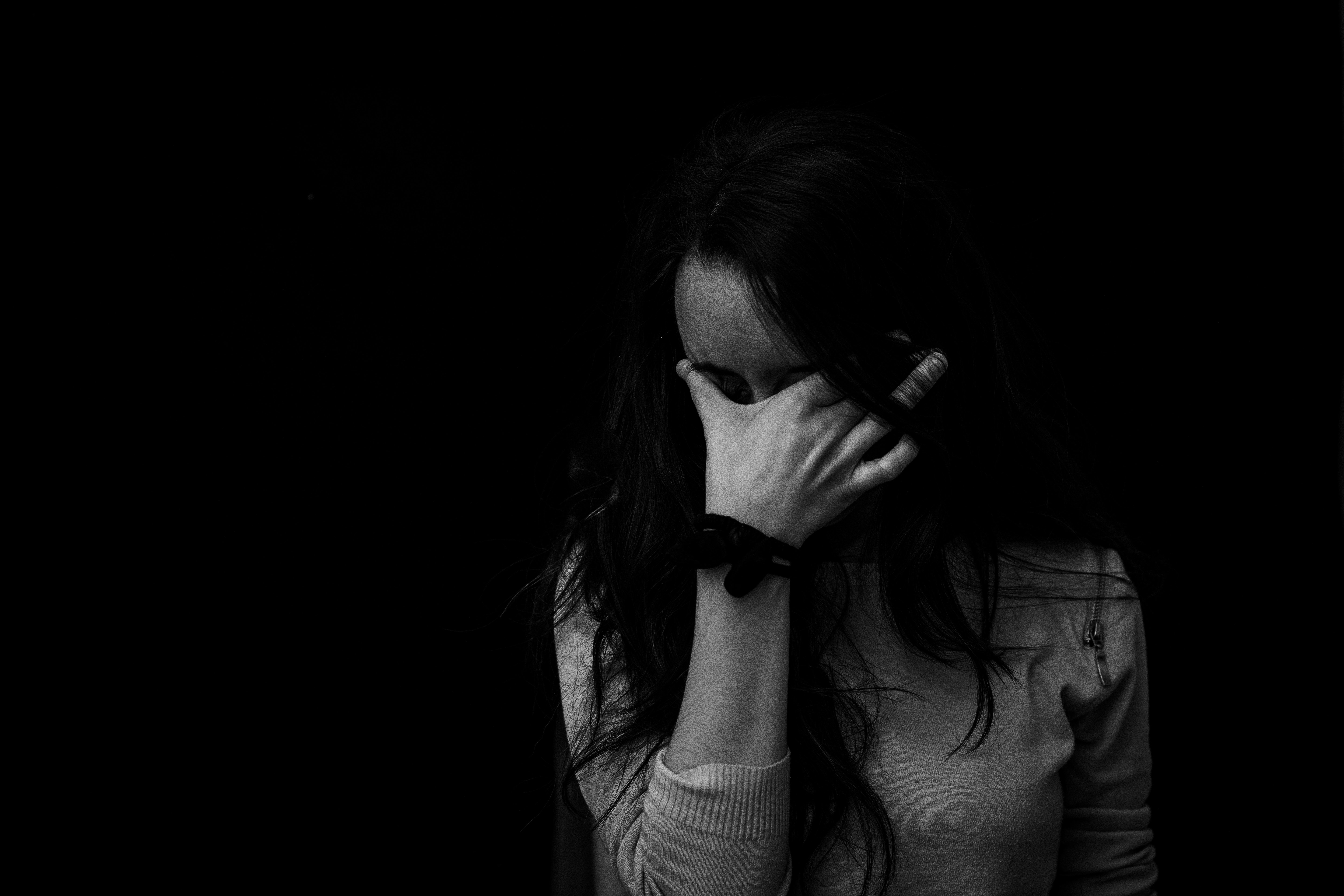 woman standing in a dark area with her hand over her face