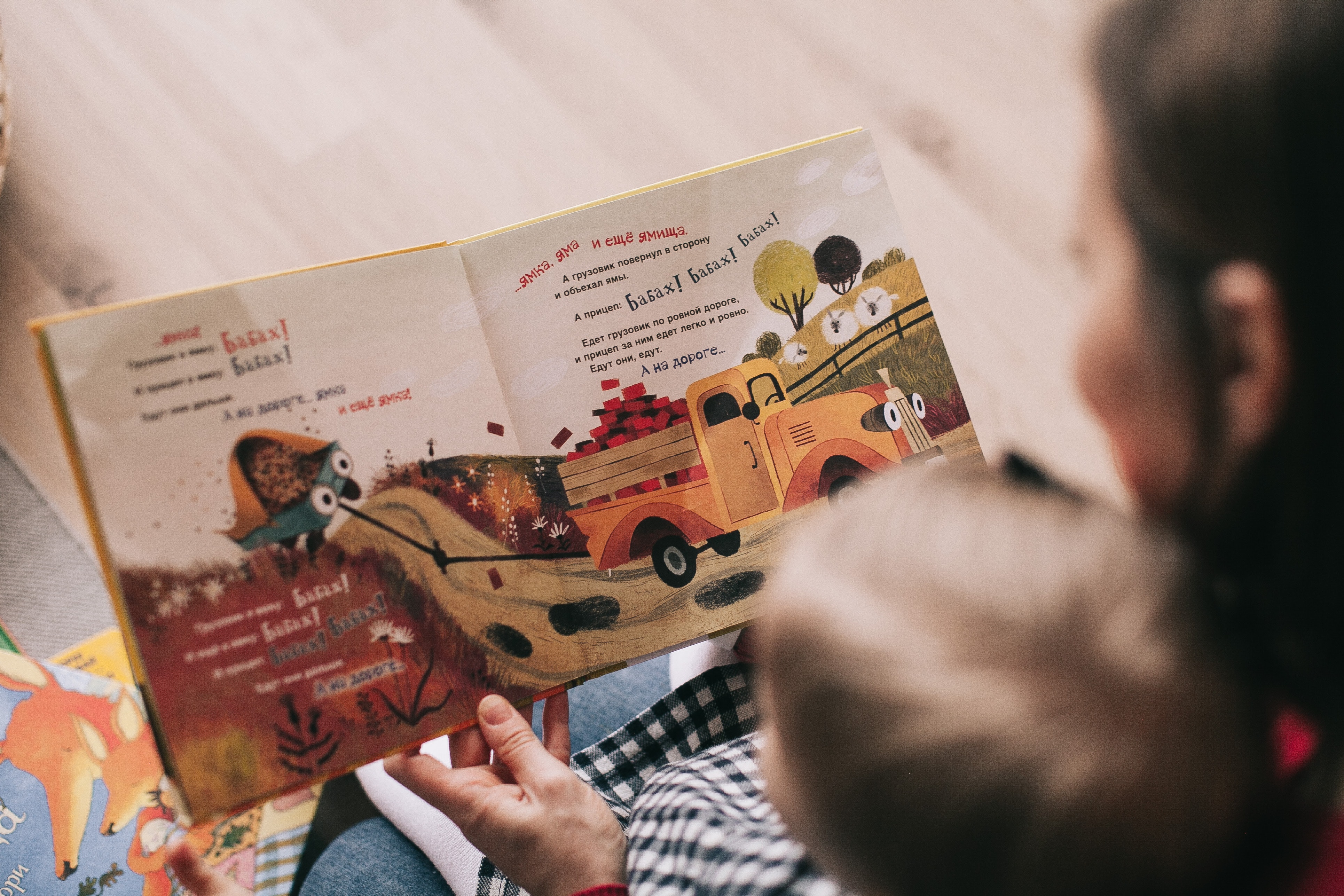 a woman reading a book to a young child in her lap