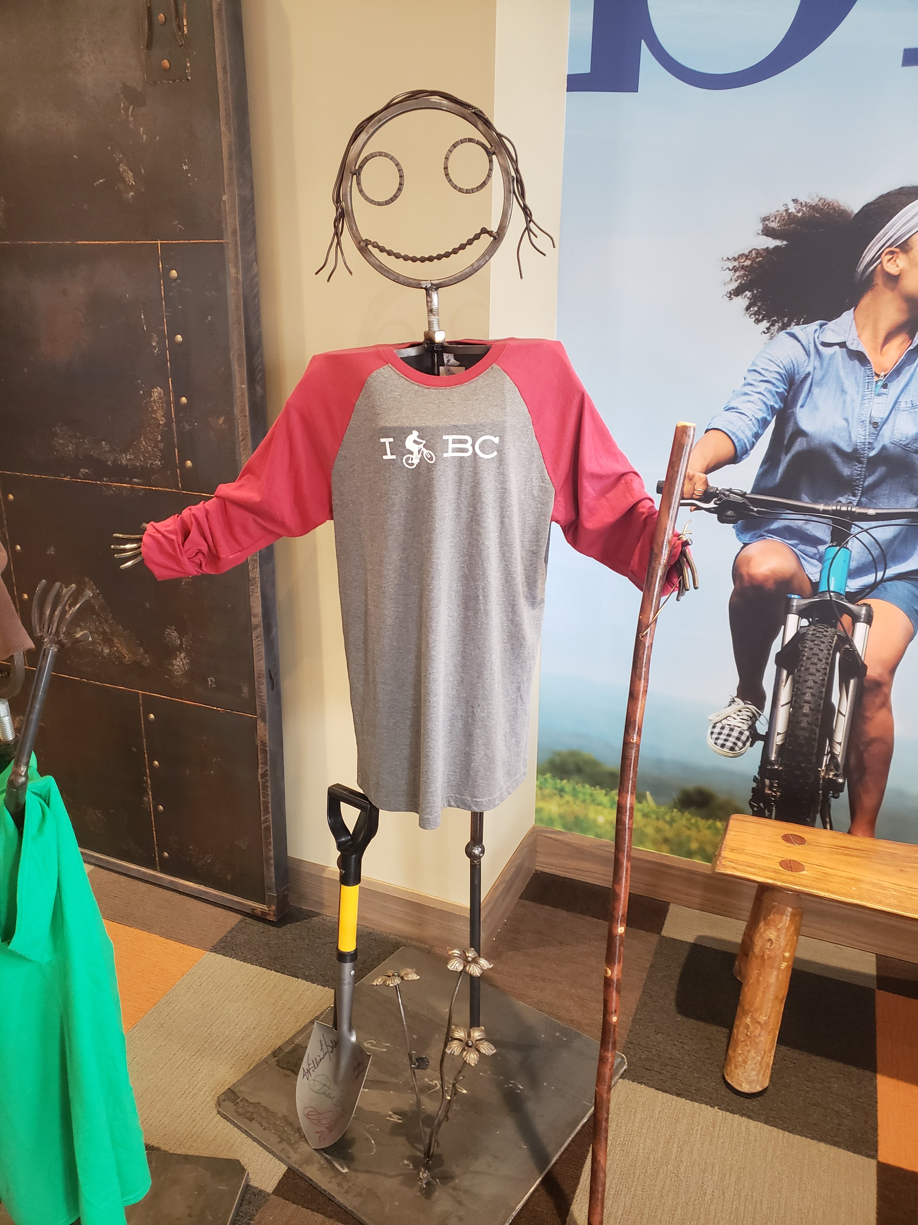 A metal mannequin wearing a I "person on a bike" BC long sleeve gray and pink shirt