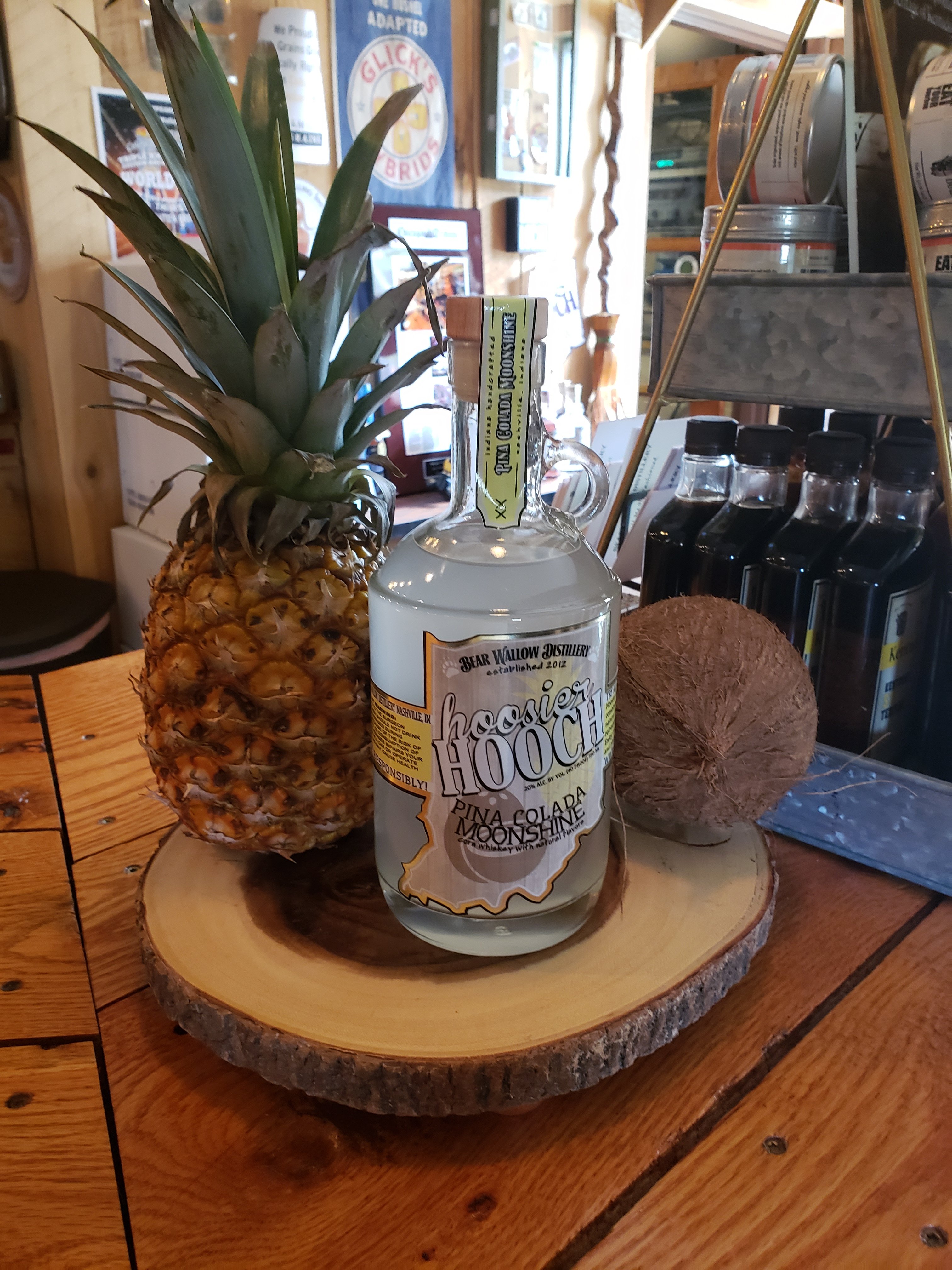 Pina Colada Moonshine bottle on wood platter with pineapple and cococut