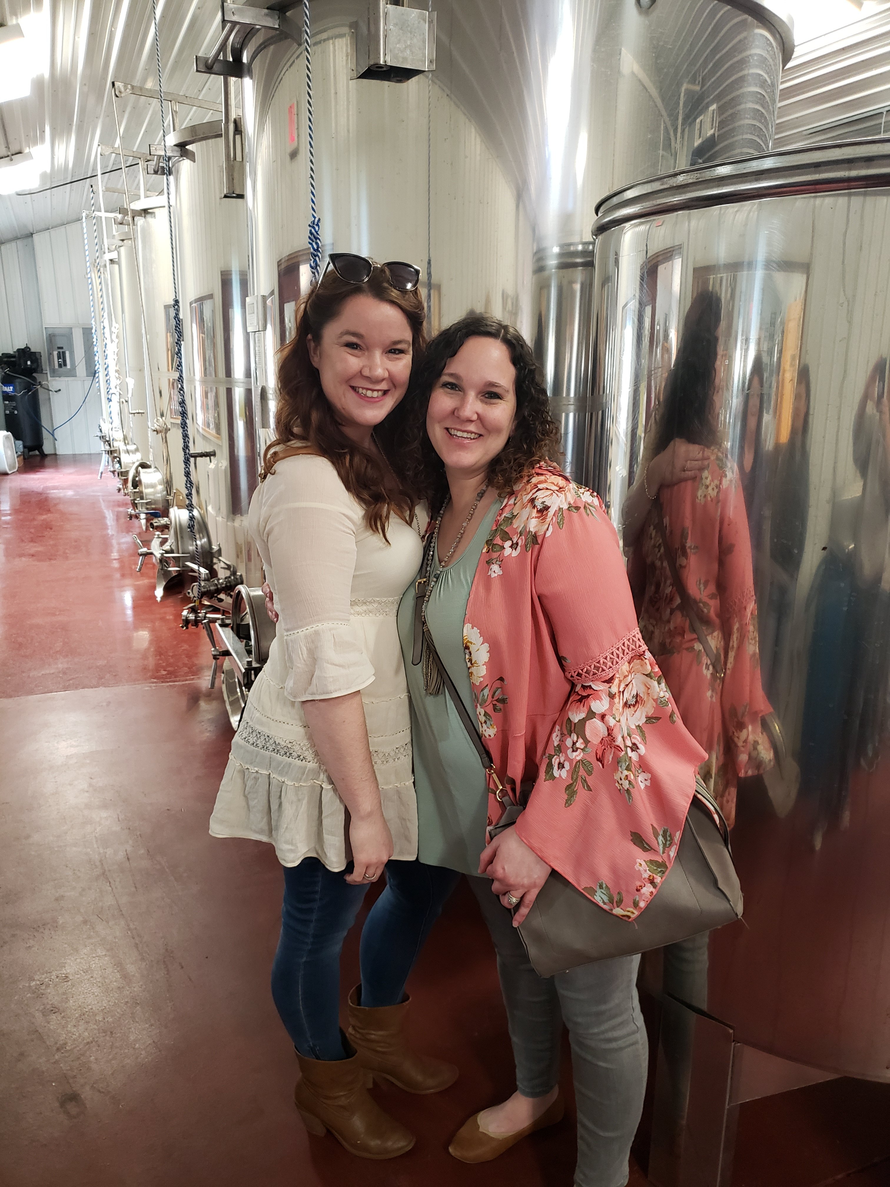 two moms giving half hugs  in front of distillery