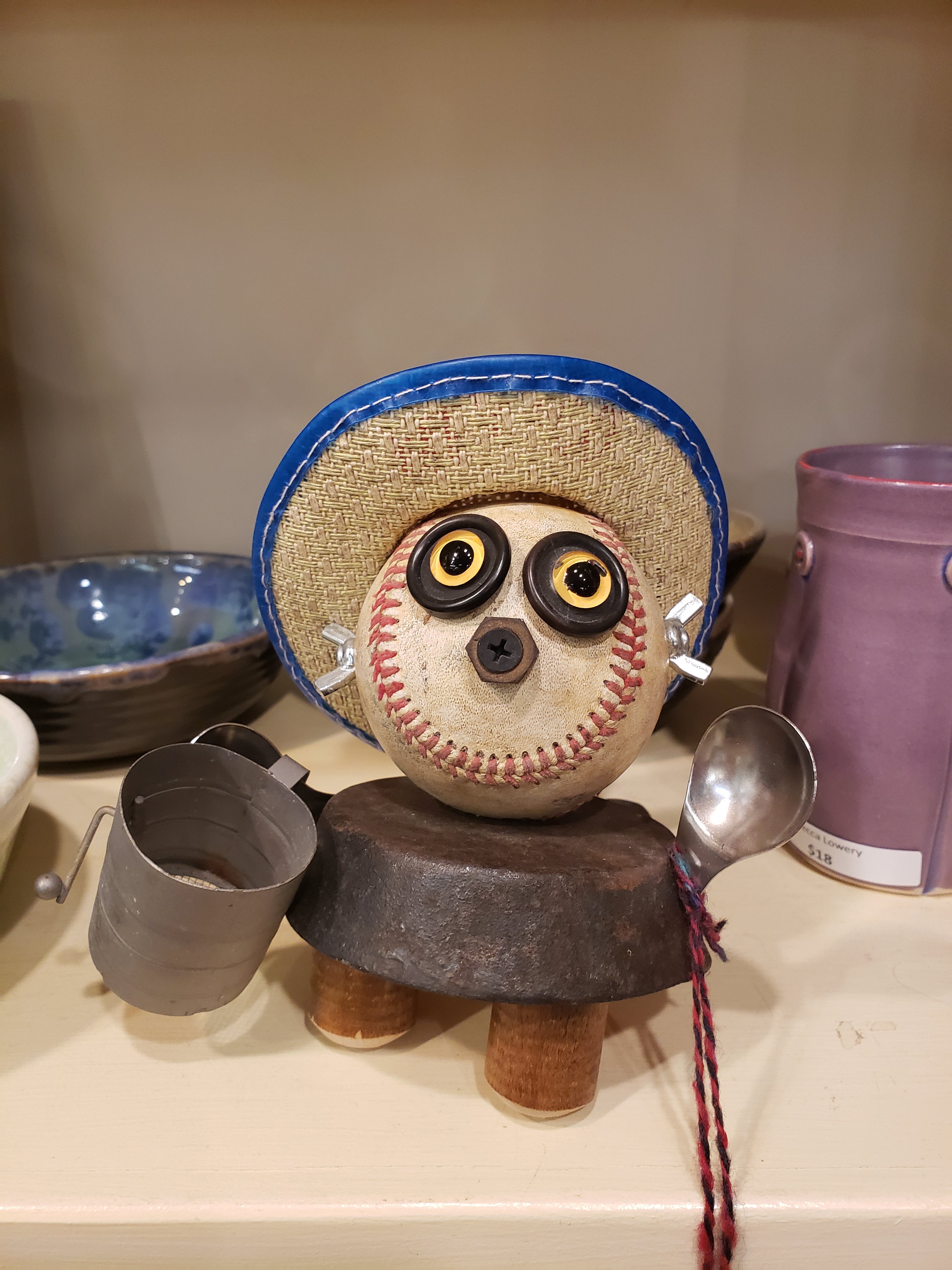 a baseball cowboy sculpture made from a baseball, a spoon, a small cast iron pan, and other household objects