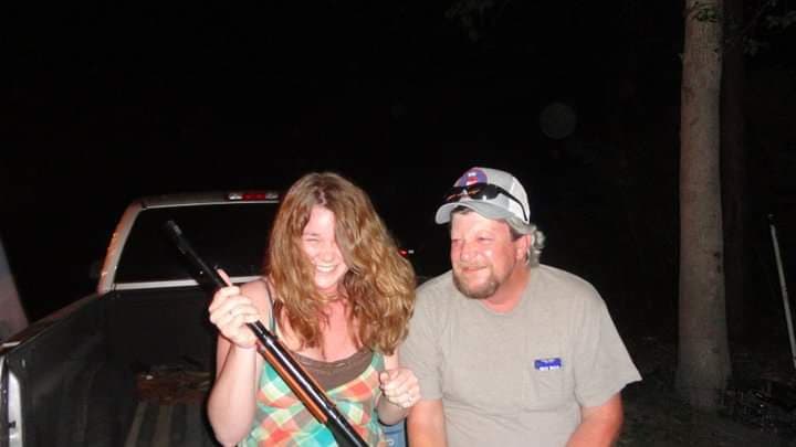 A man and a woman sitting on the tailgate of a truck in the dark