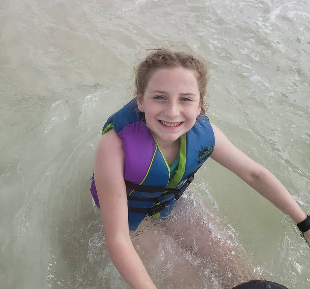 a young girl wearing a life jacket going into a water