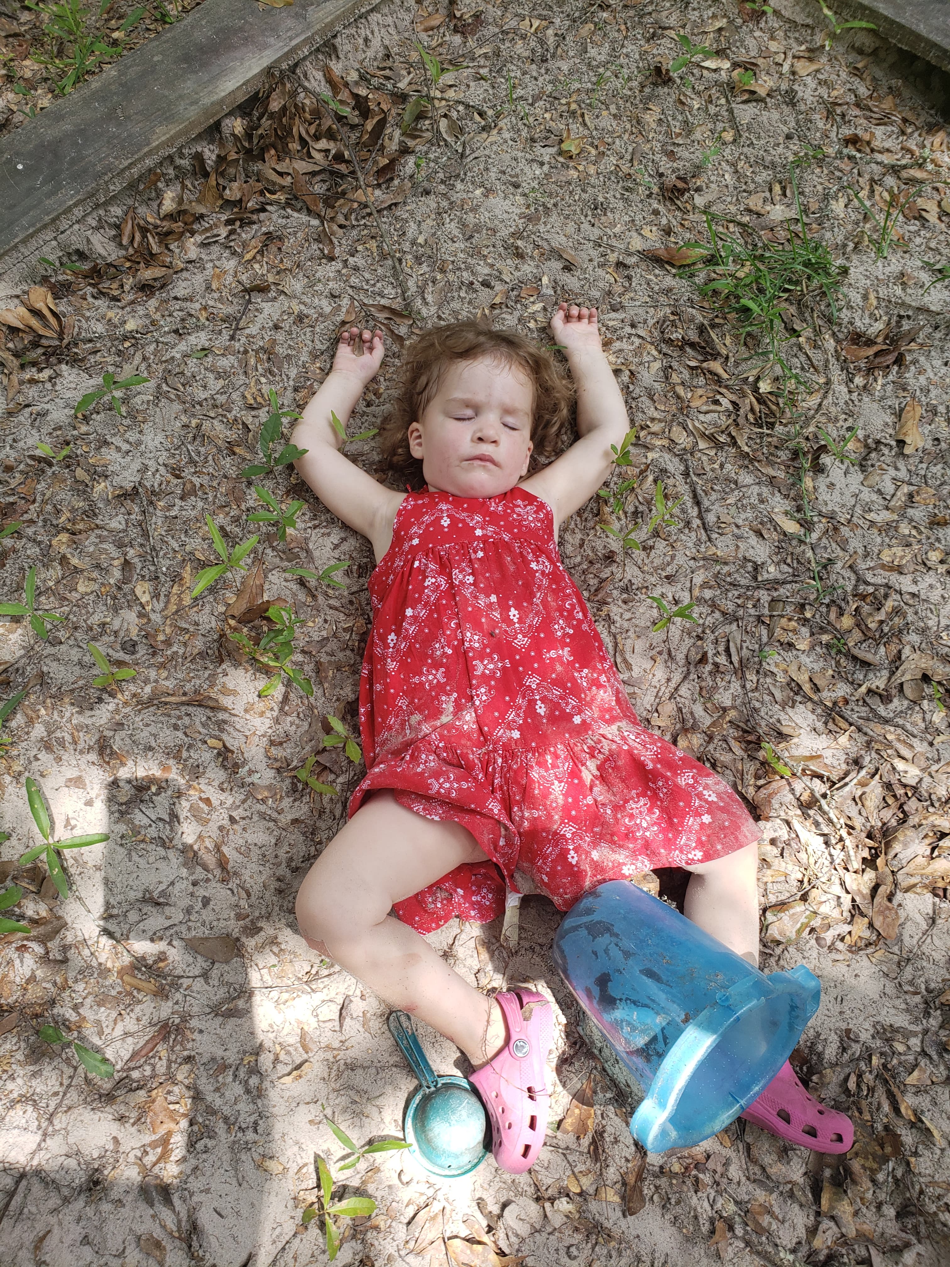 A toddler girl laying the sand