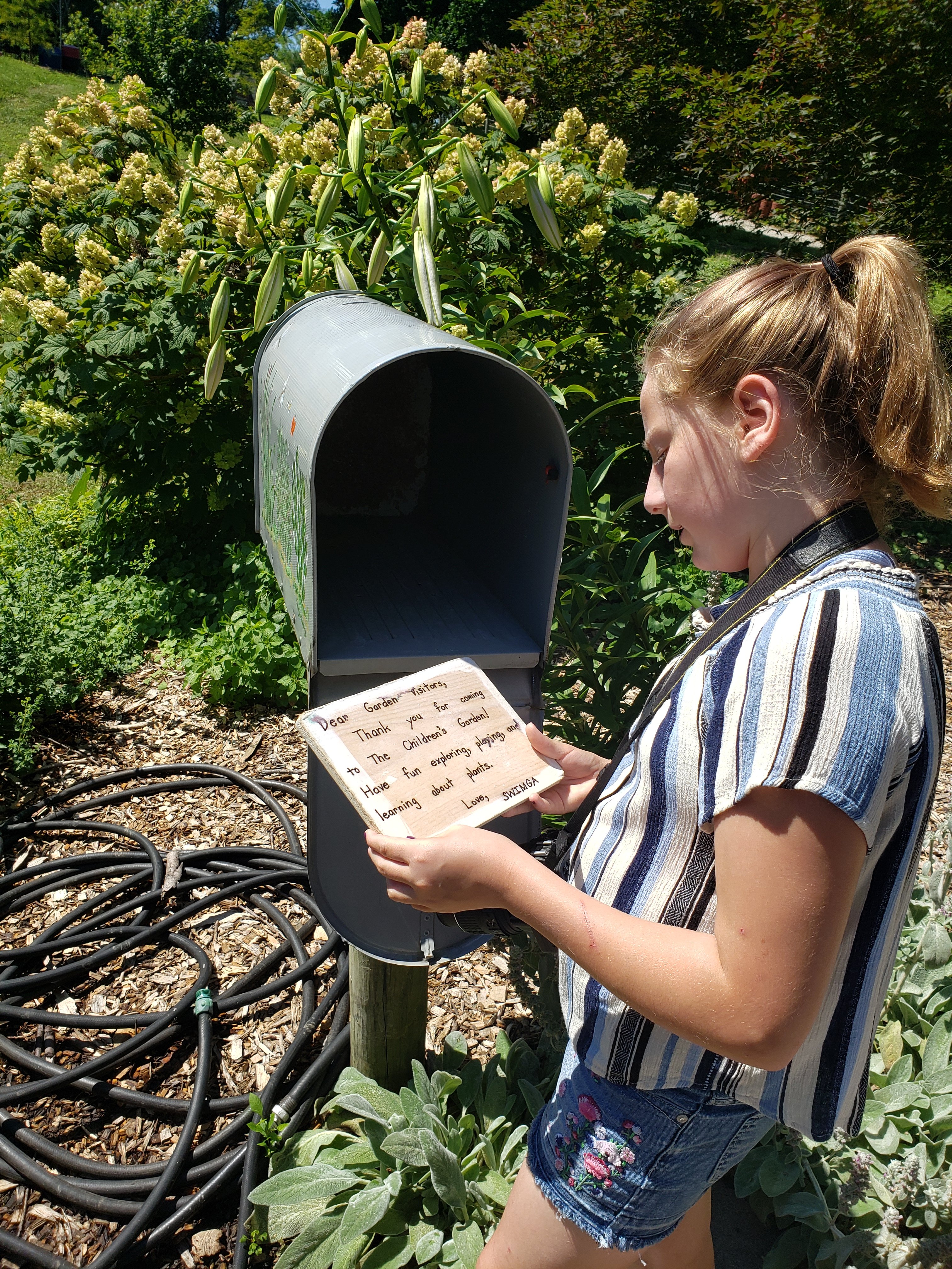 girl with a camera around her neck reading apiece of zoo mail