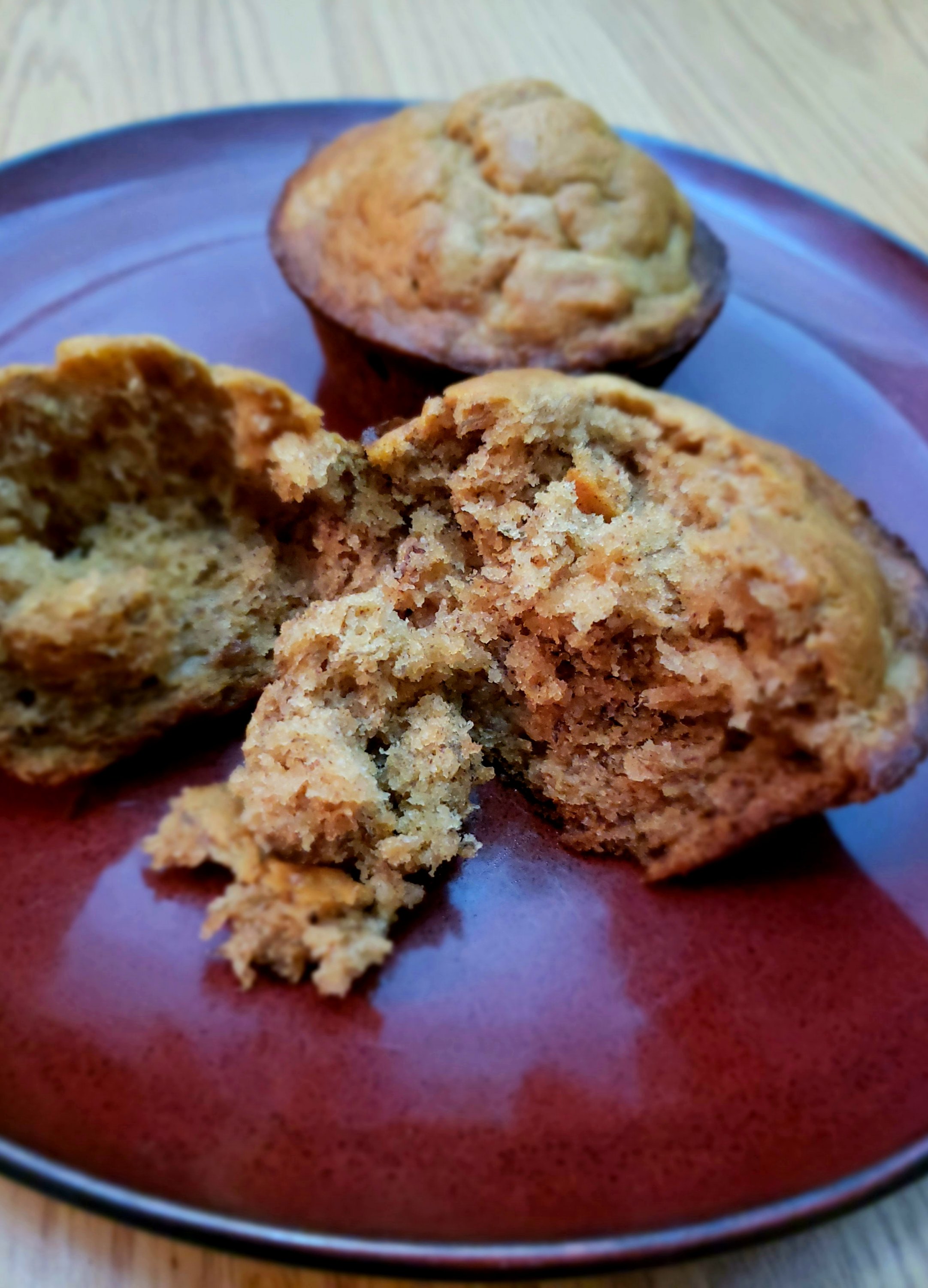 two Banana Peanut Muffins on a plate, one muffin is broken up