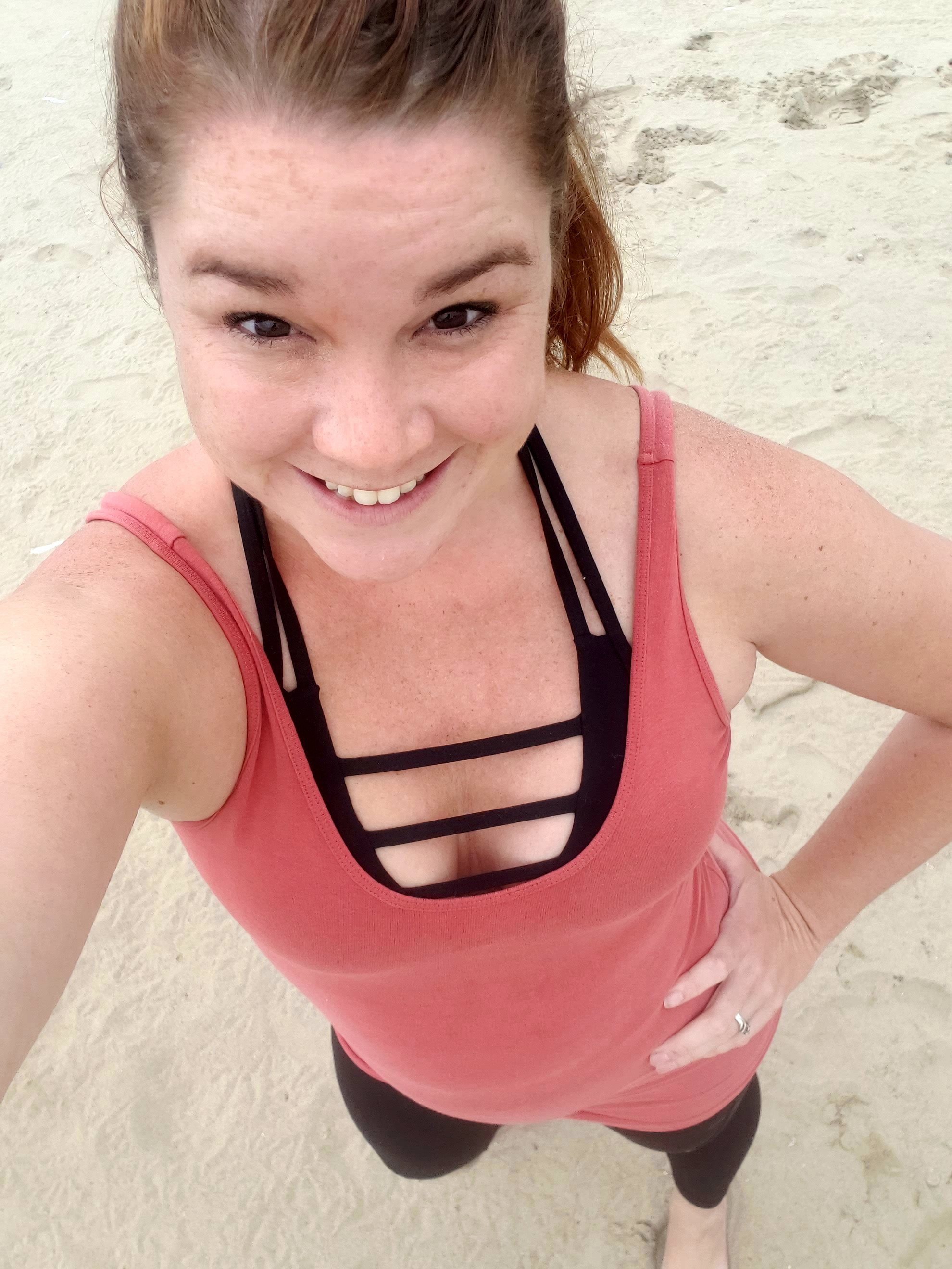 woman wearing ZYIA outfit taking a selfie on the beach