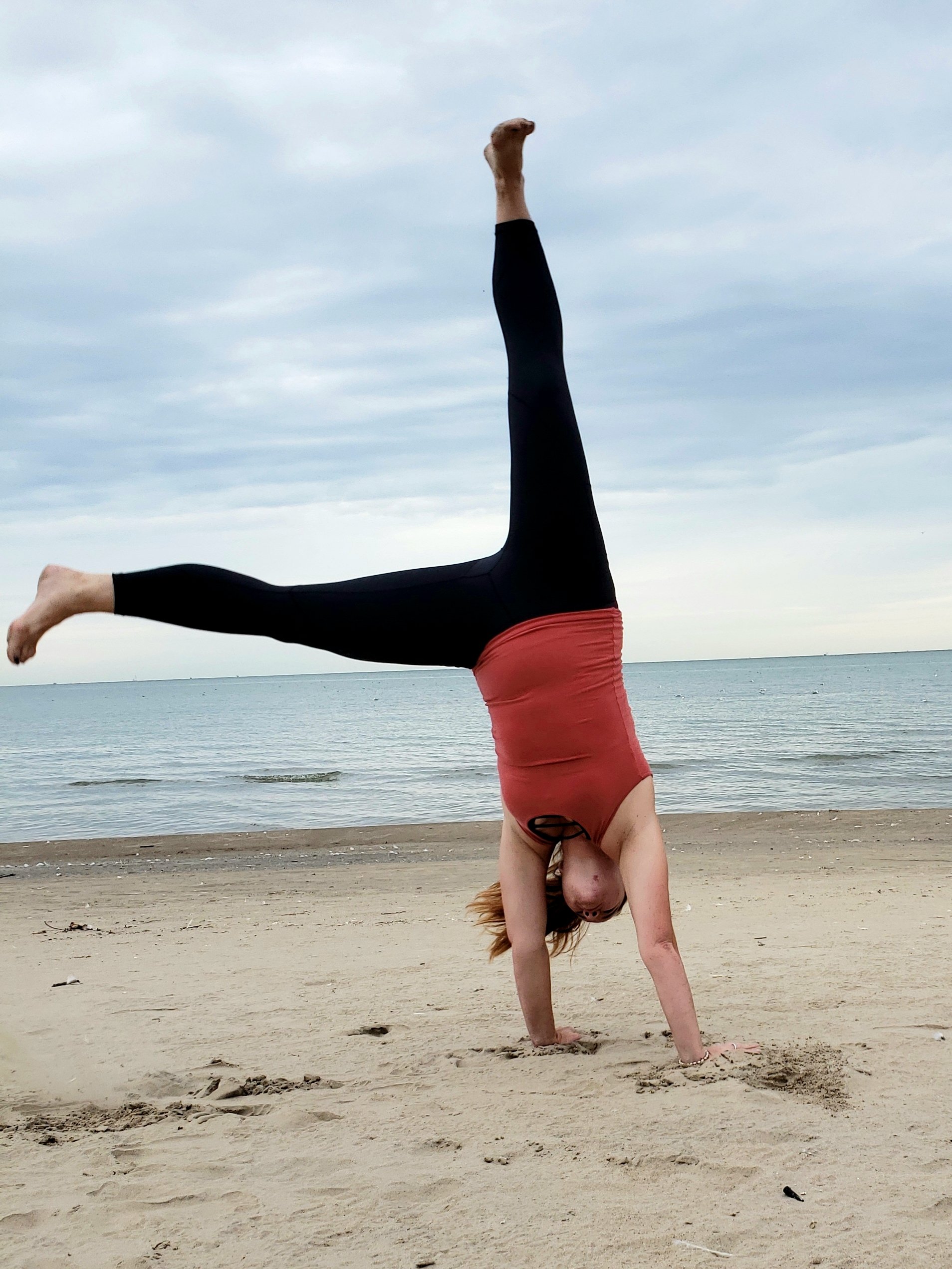 Woman wearing ZYIA outfit doing a cartwheel on the beach