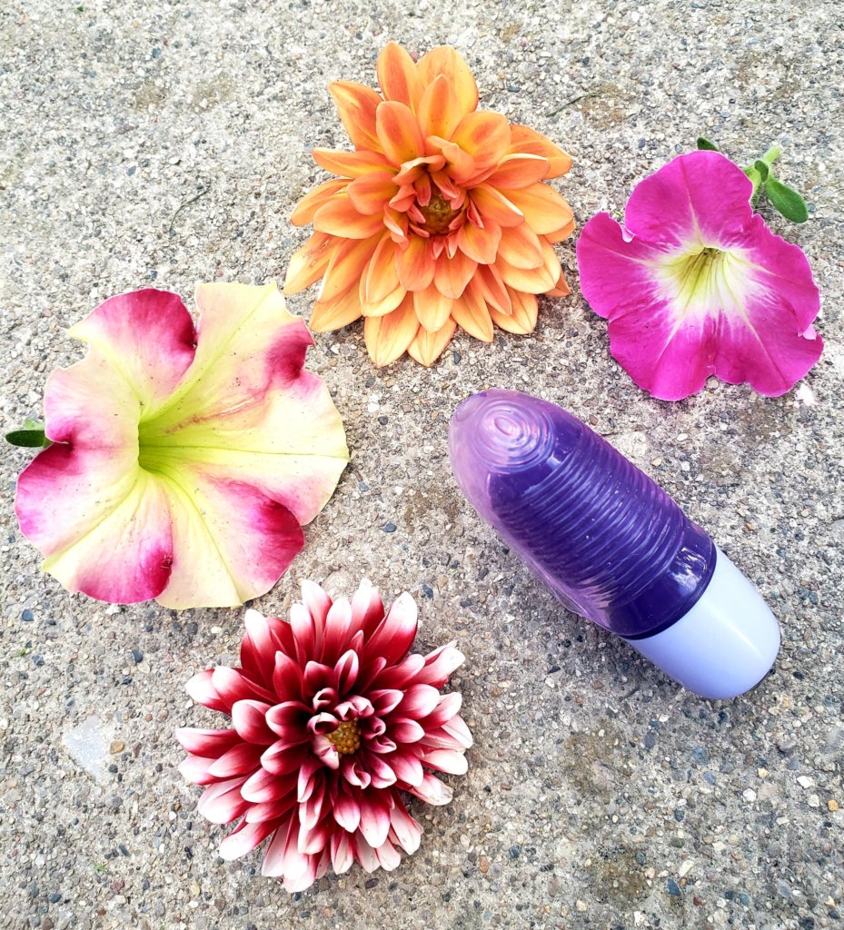 finger vibrator with flower laying around it on cement surface